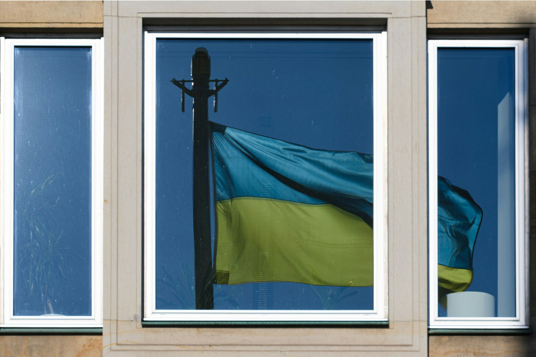 Eine Flagge der Ukraine spiegelt sich in einem Fenster (Symbolbild).