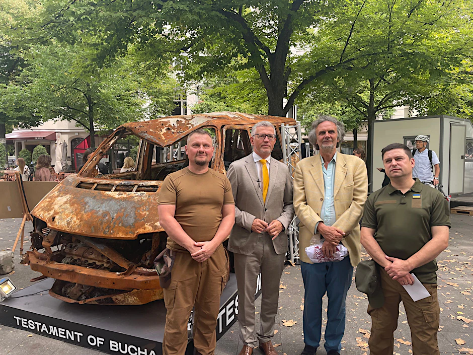 Der Botschafter der Ukraine André Melnyk, der Bezirksbürgermeister Oliver Schruoffeneger und die beiden ukrainischen Initiatoren Andriy Radnyuk und Roman Semenyshyn-Braescu vor dem verbrannten Auto, in dem vier Menschenleben ihr Ende fanden.