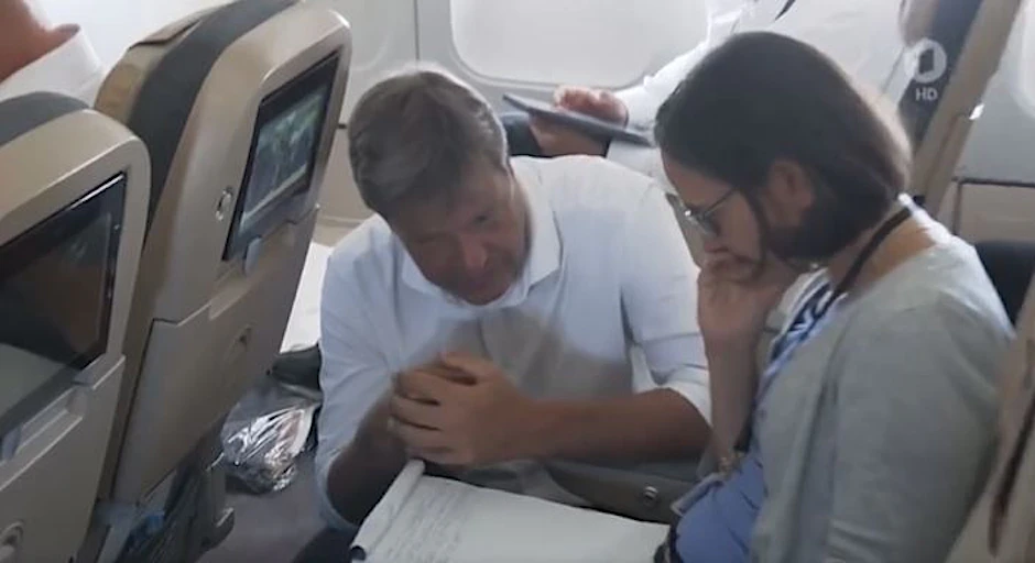 Robert Habeck sitzt ohne Maske im Regierungsflieger neben einer Frau.