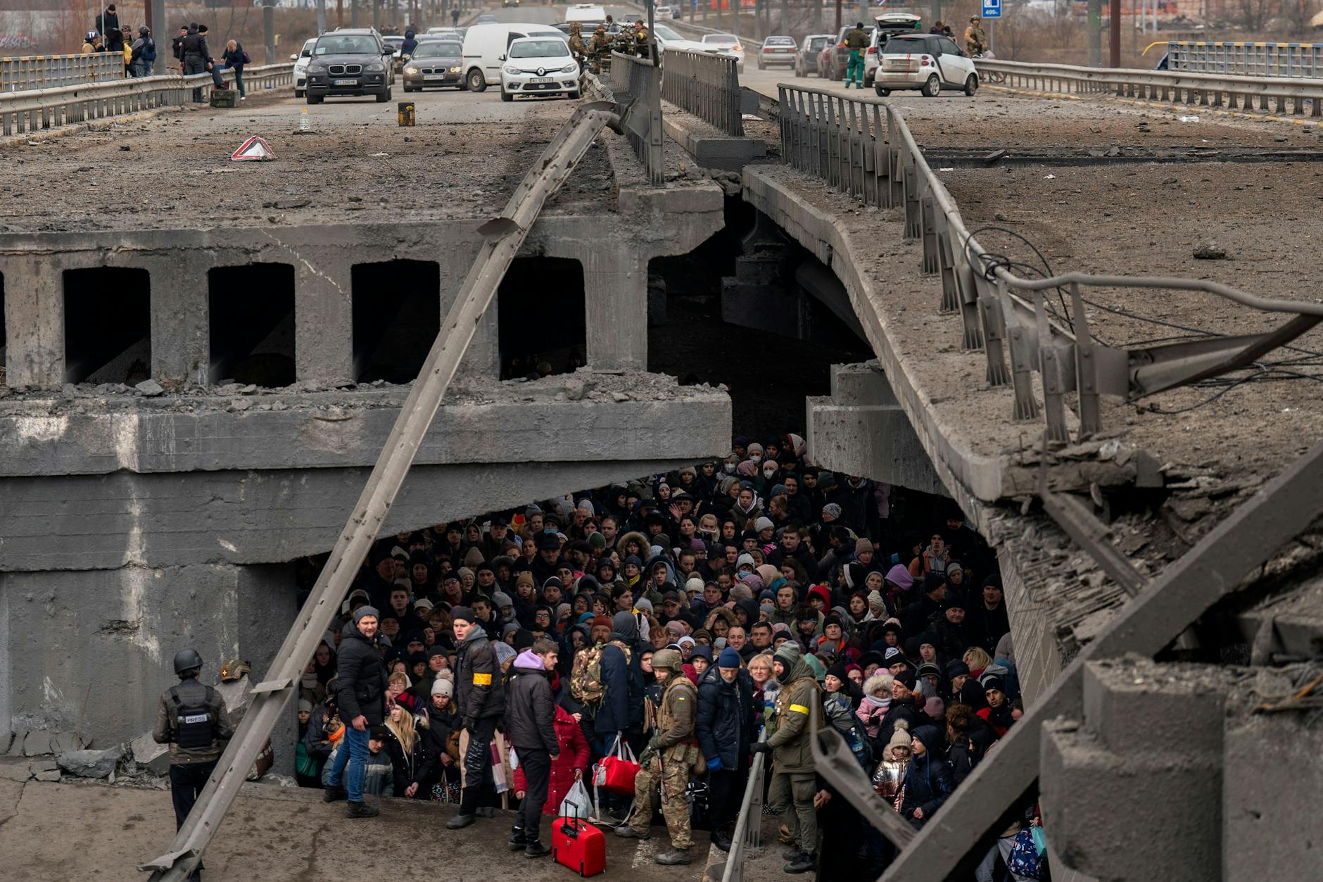 Ukrainer drängen sich unter einer zerstörten Brücke in Irpin bei Kiew.