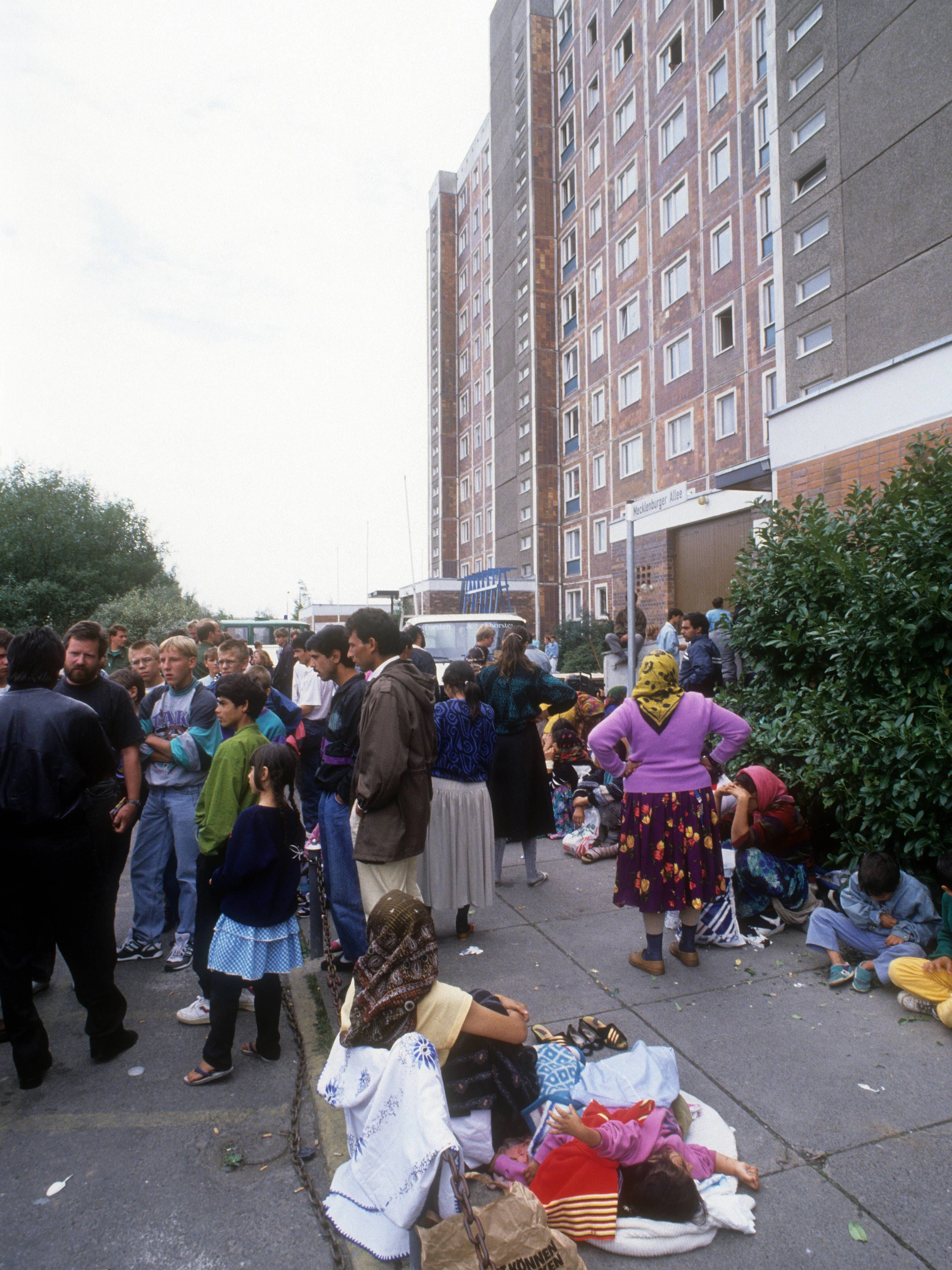Eine Gruppe Geflüchteter steht auf der Straße nach den Anschlägen von 1992 in Rostock-Lichtenhagen.