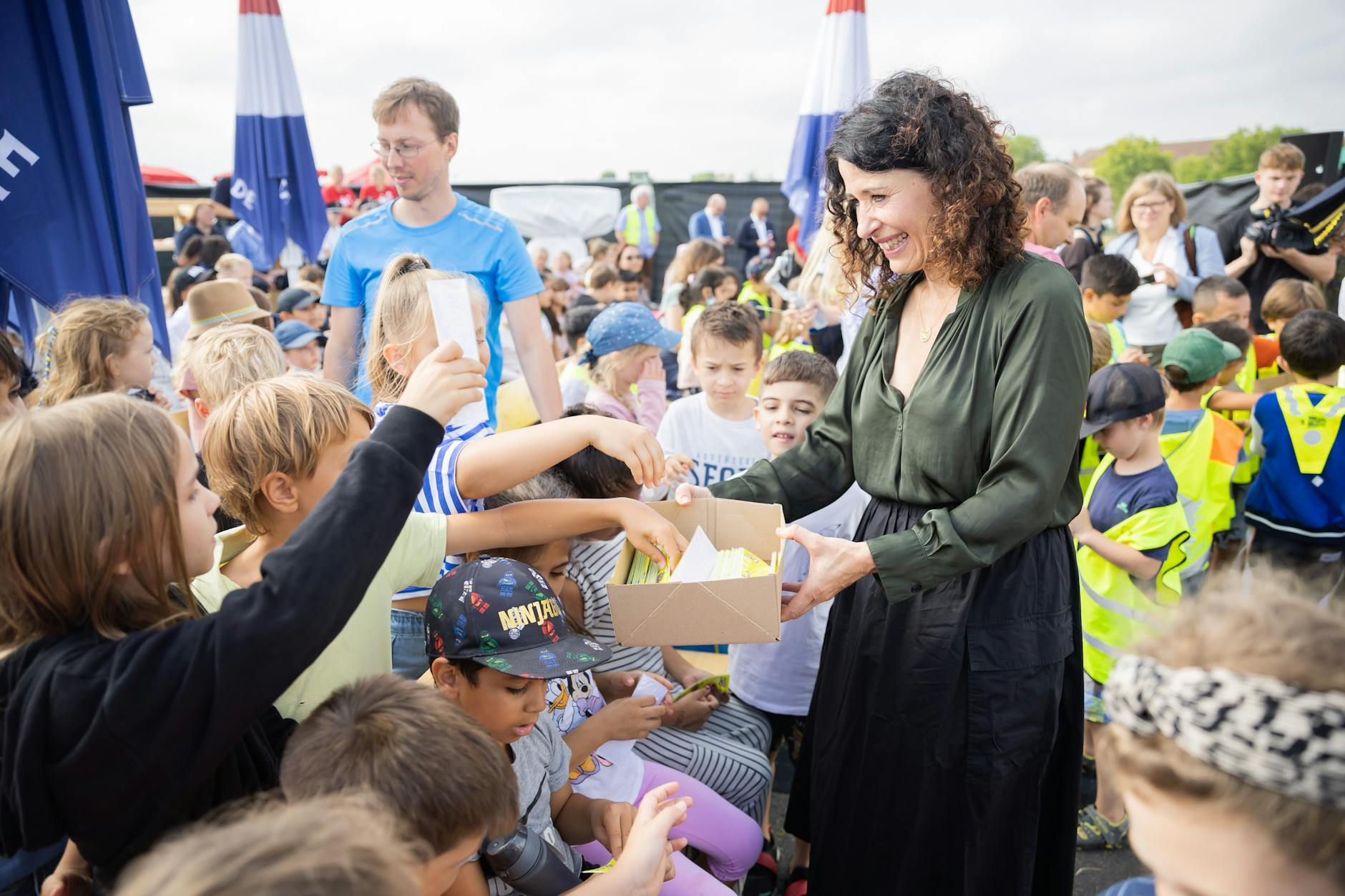 Mobilitätssenatorin Bettina Jarasch verteilt Reflektoren an Erstklässler.