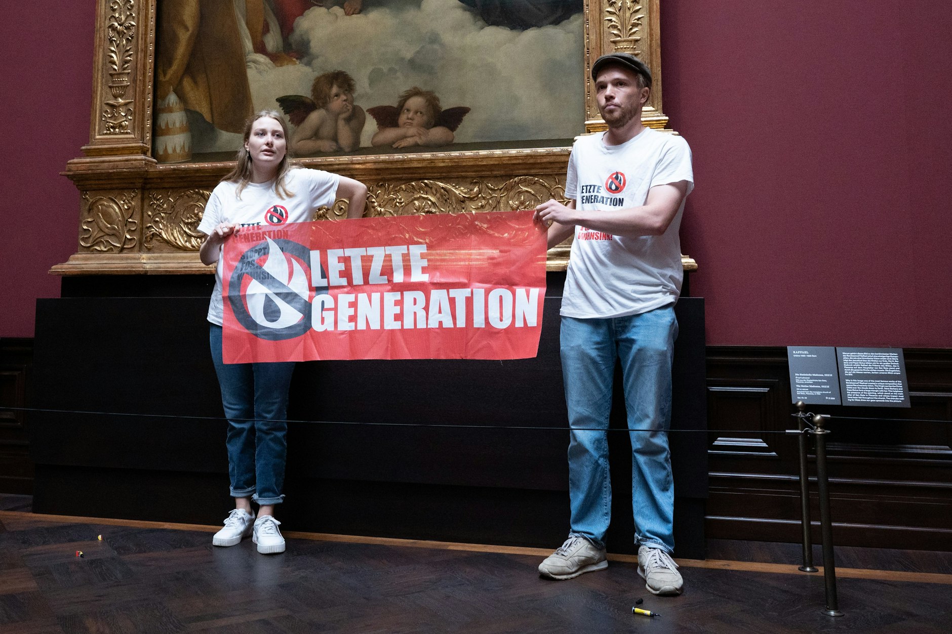 Dresden: Zwei Umweltaktivisten der Gruppe „Letzte Generation“ stehen mit einem Banner in der Gemäldegalerie Alte Meister an dem Gemälde „Sixtinische Madonna“ von Raffael, die Hände festgeklebt am kostbaren Goldrahmen.&nbsp;