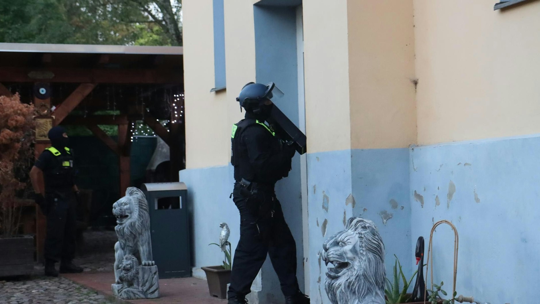 Ein Polizist mit Ramme an der Tür der Remmo-Villa in Alt-Buckow.