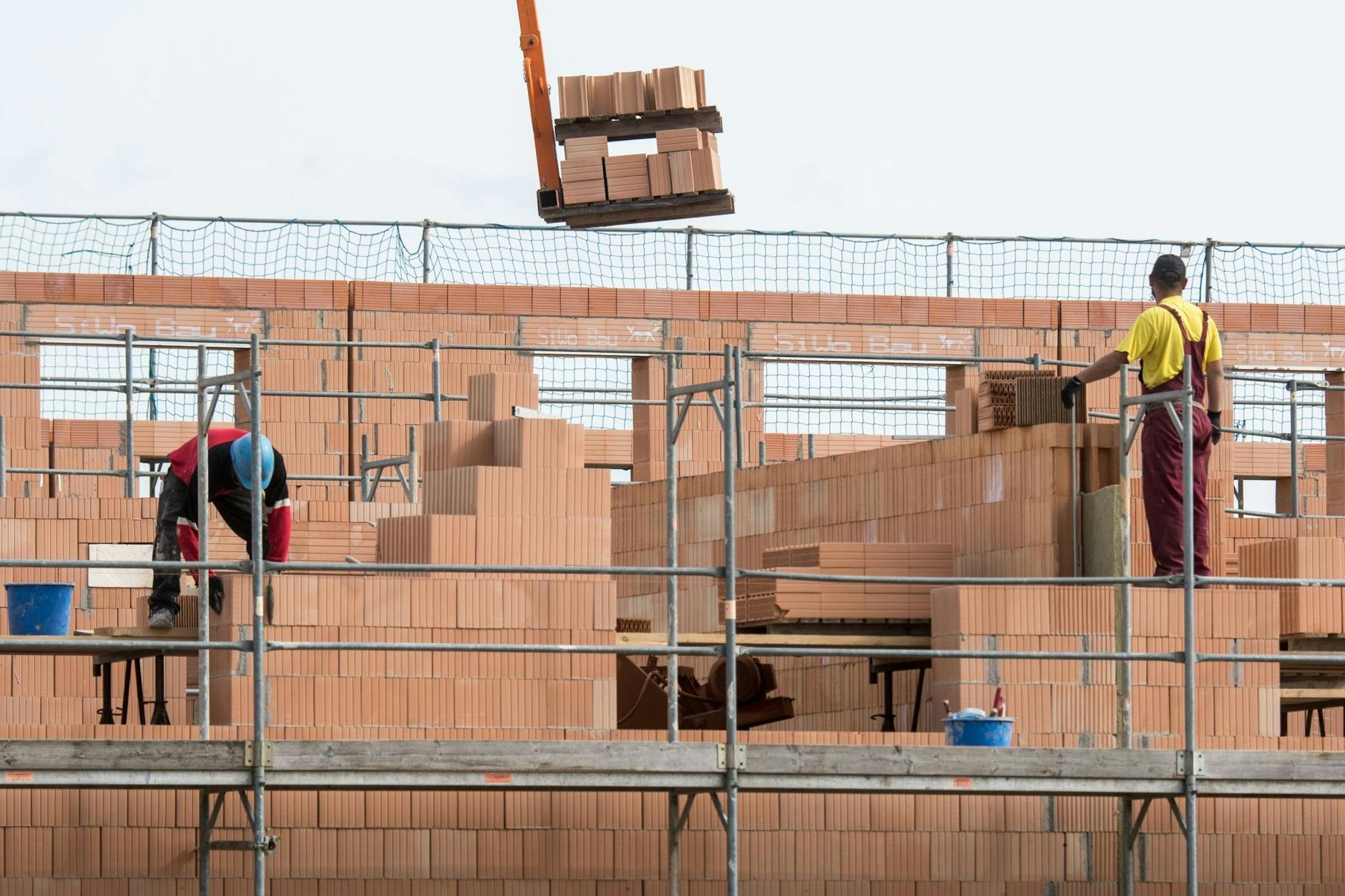 ARCHIV - Maurer arbeiten an einem Rohbau von Reihenhäusern in einer Neubausiedlung. Besonders hart getroffen von der Auftragsflaute ist der Wohnungsbau.