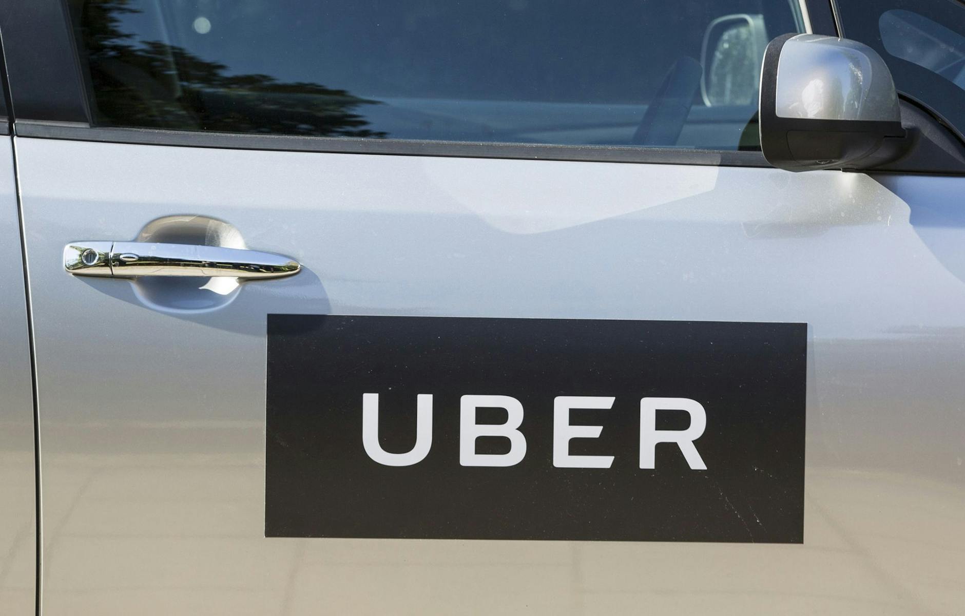 ARCHIV - Ein Logo von Uber auf einer Autotür. d