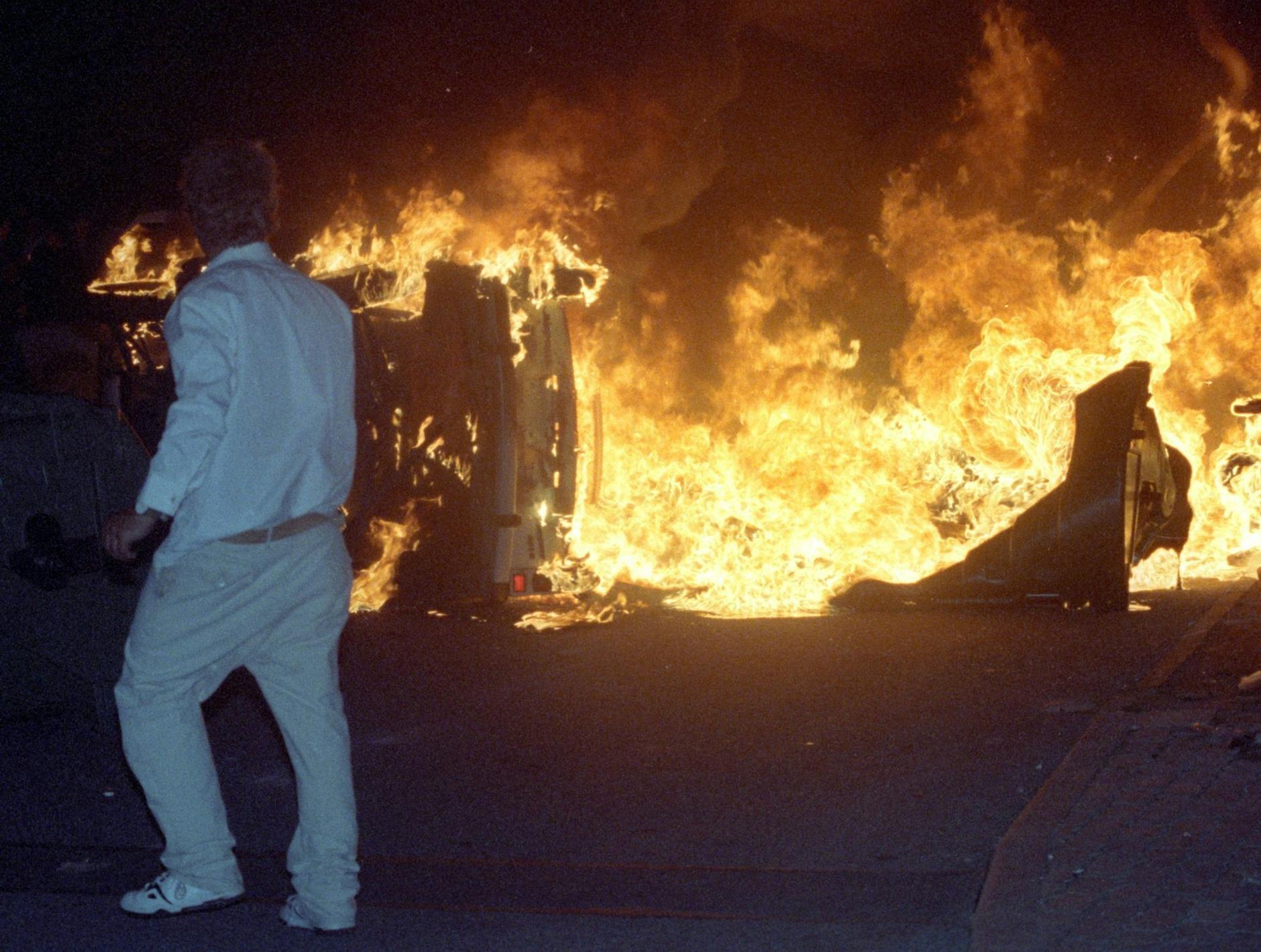 ARCHIV - Ein Mann steht bei den Ausschreitungen 1992 vor dem zentralen Asylbewerberheim in Rostock-Lichtenhagen. k/dpa
