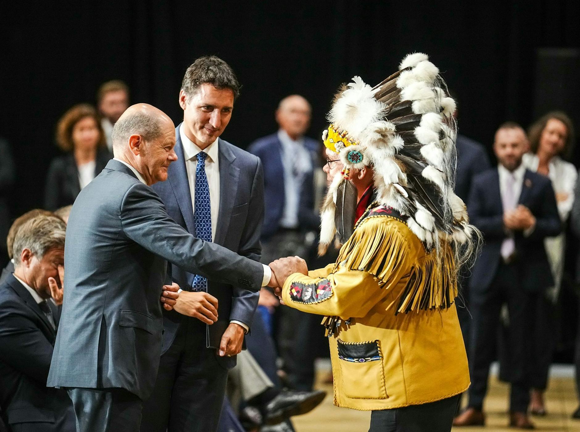 Bundeskanzler Olaf Scholz (l) und der kanadische Premierminister Justin Trudeau werden von Misel Joe, dem Chief der Miawpukek, auf Neufundland begrüßt.