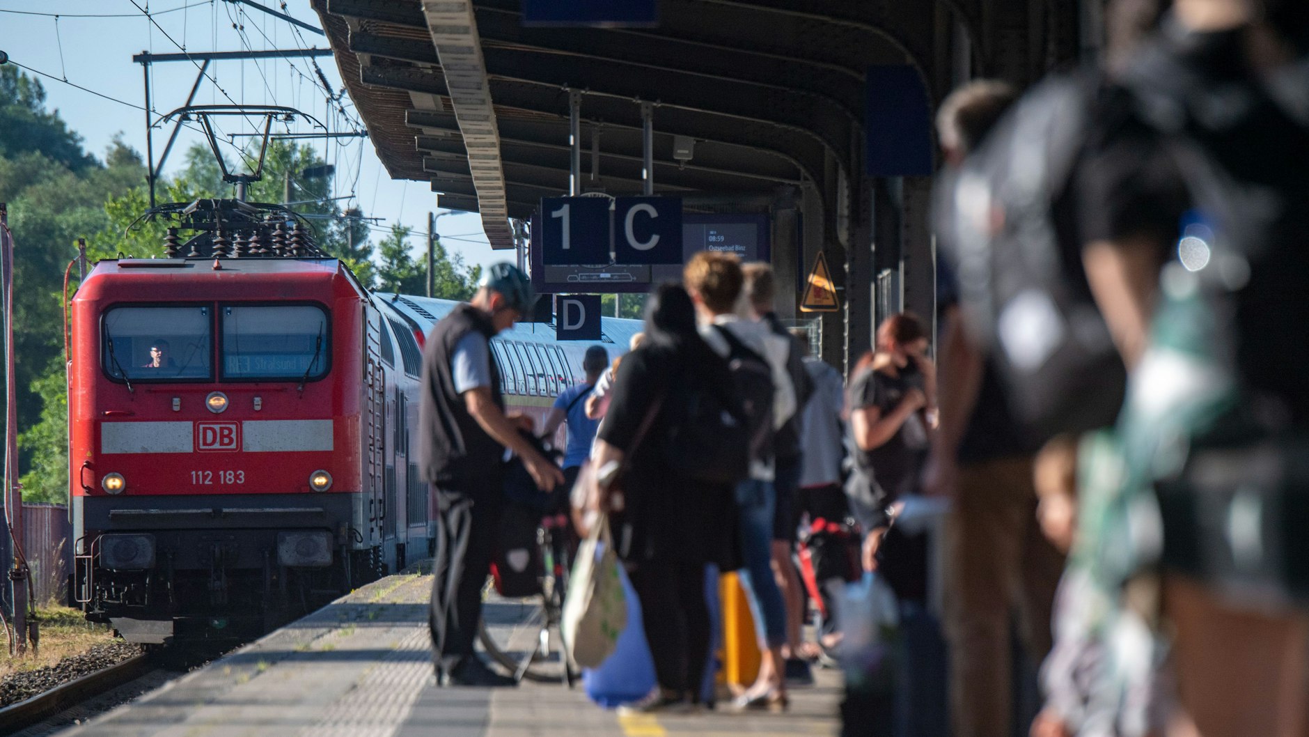 Fahrgäste warten im Bahnhof auf eine Regionalbahn. Das Sommerwetter nutzen viele Urlauber und Tagesgäste für einen Strandbesuch an der Ostseeküste und nutzen dafür auch das Neun-Euro-Ticket der Bahn.
