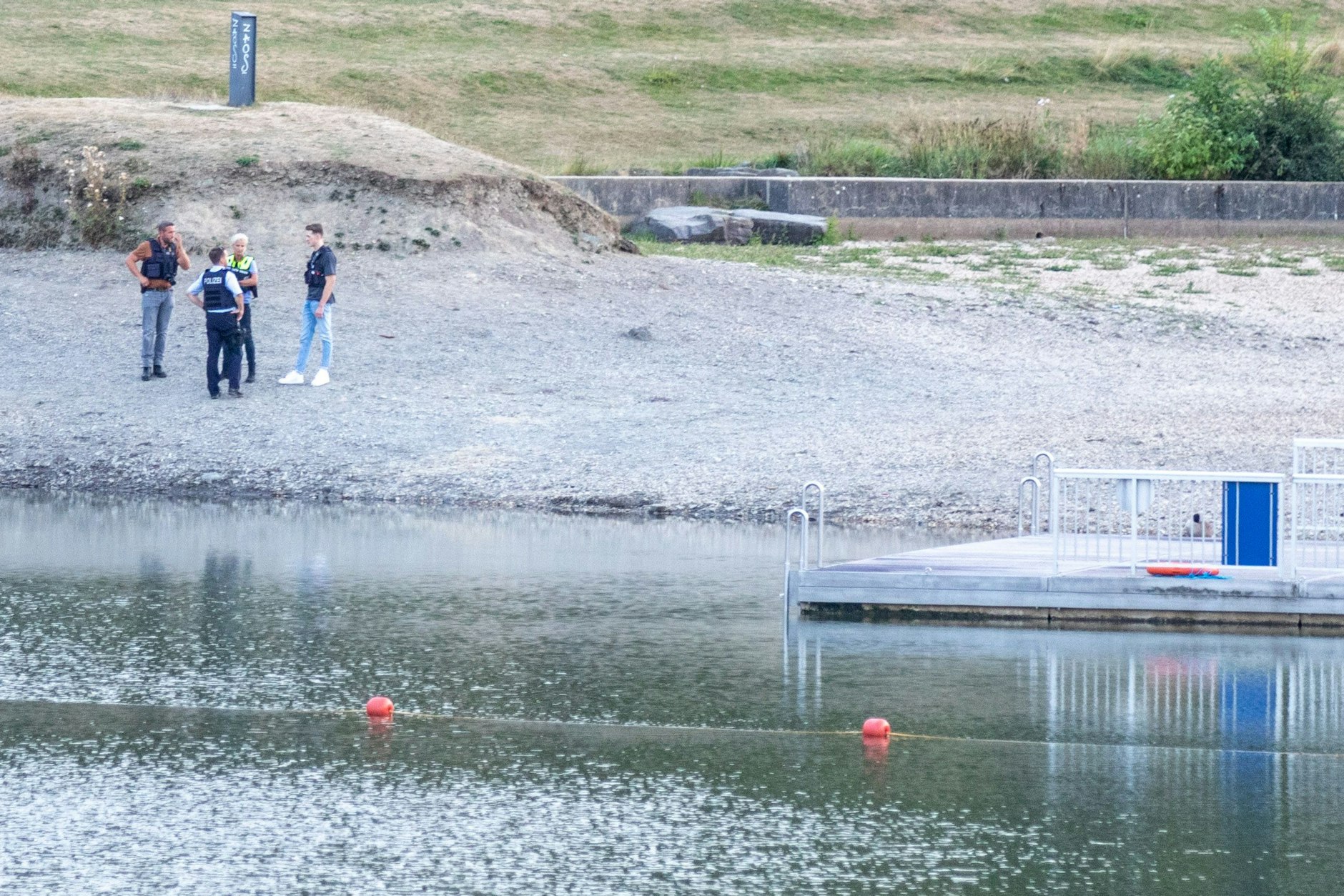 Polizisten stehen am Ufer des Eiserbachsees im Rurseezentrum. Nach einem Badeunfall in dem Badesee bei Aachen sind zwei Kinder gestorben.