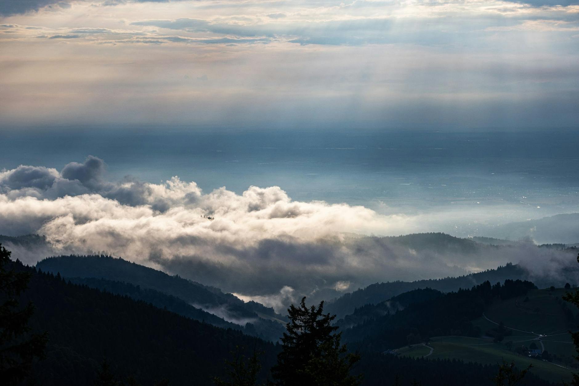 Wolken ziehen über die Ausläufer des Schwarzwalds, während im Hintergrund die Rheinebene zu sehen ist.