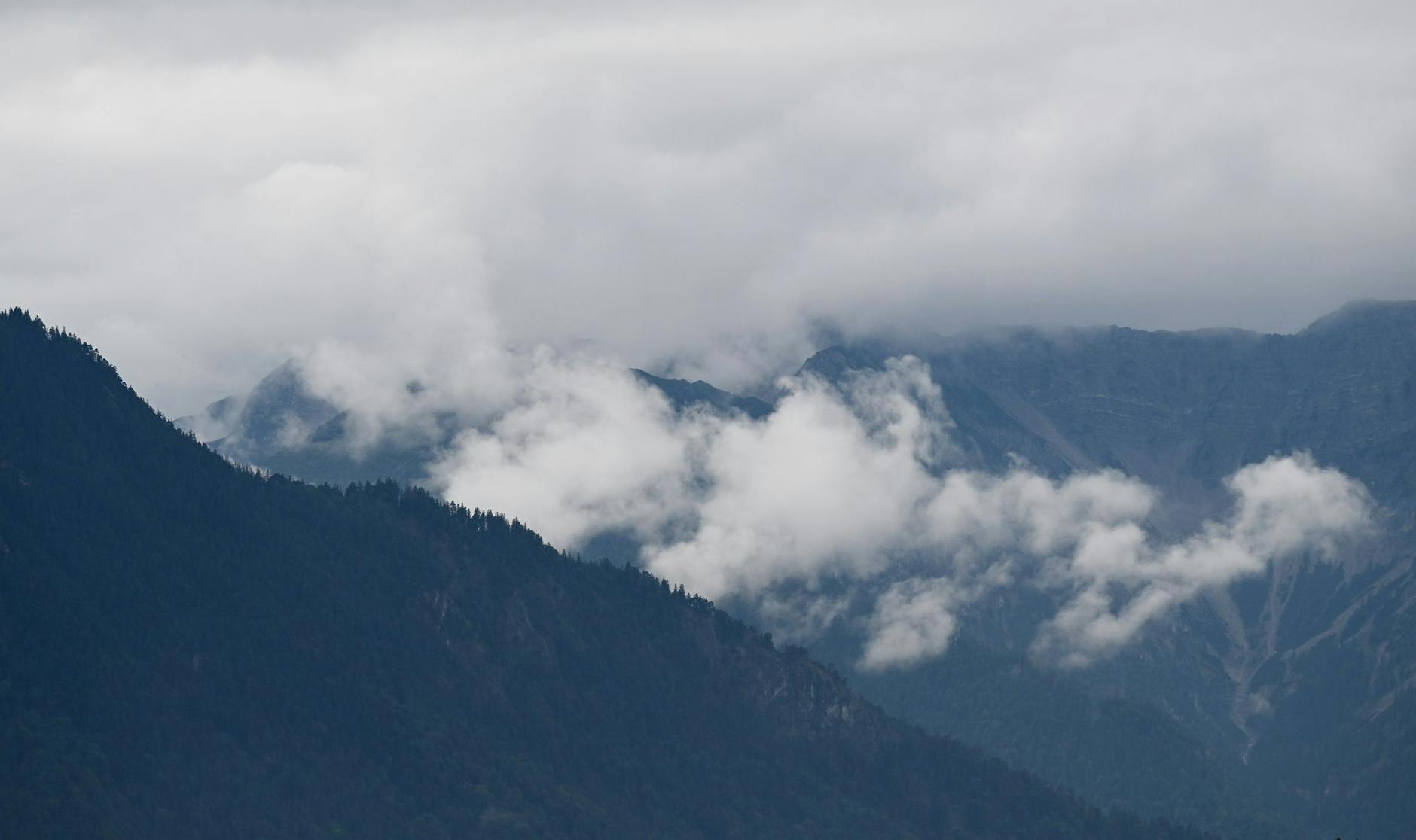 Wolkenfetzen schieben sich am Estergebirge in Bayern entlang.