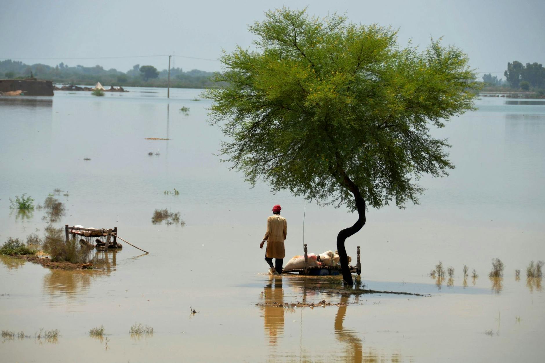 Flut in Pakistan: Ein Mann versucht mit Feldbetten, brauchbare Gegenstände zu retten.
