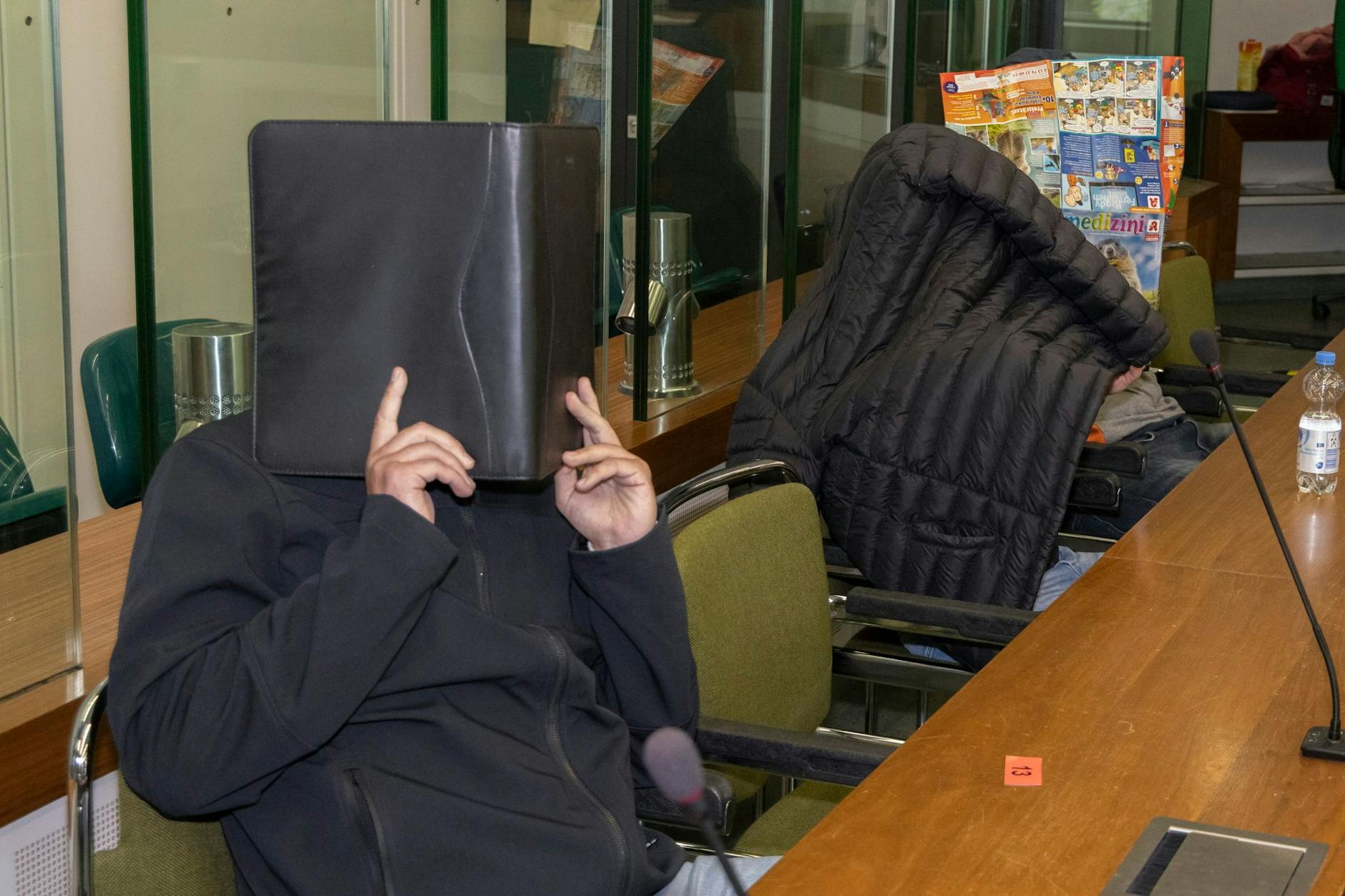 Die Angeklagten verstecken im Gerichtssaal ihre Gesichter.
