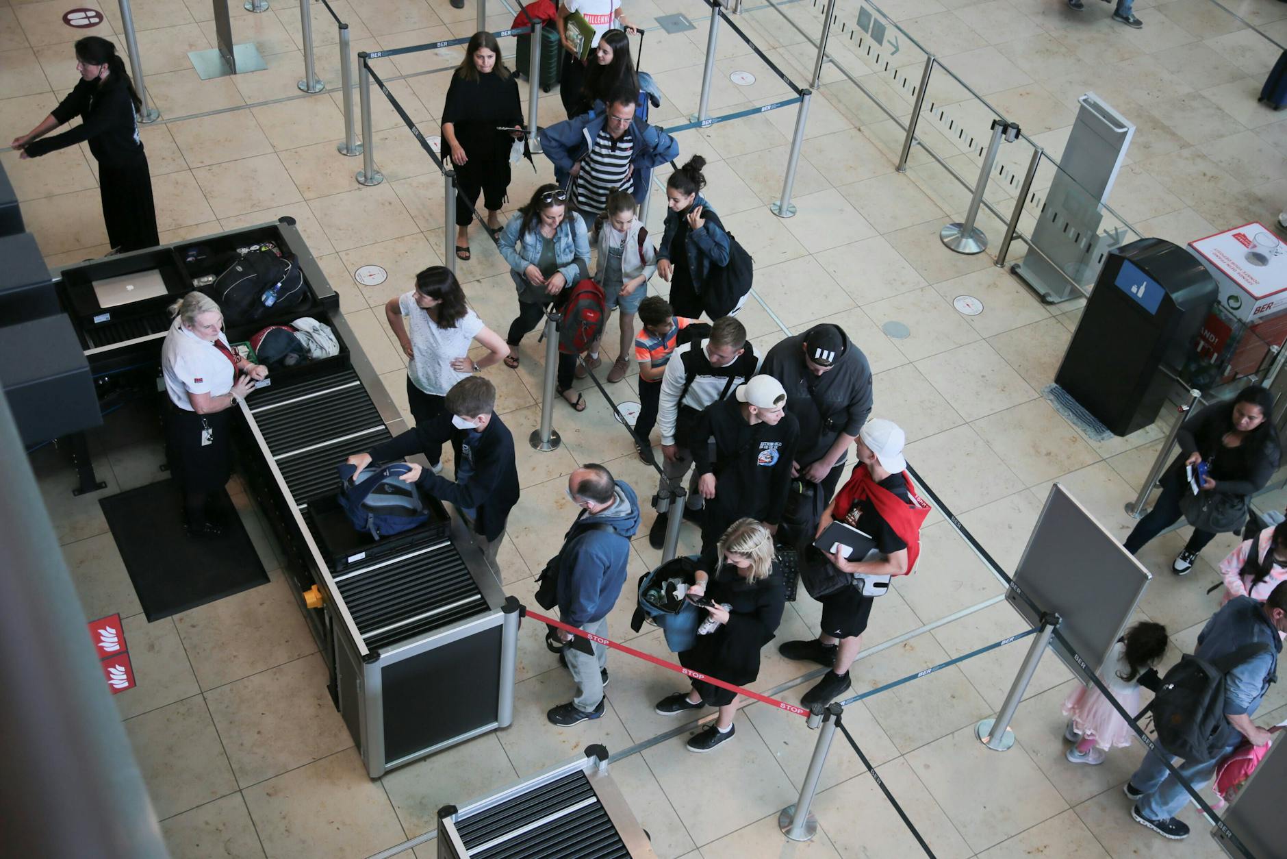 Menschen am Flughafen in der Warteschlange beim Sicherheits-Check