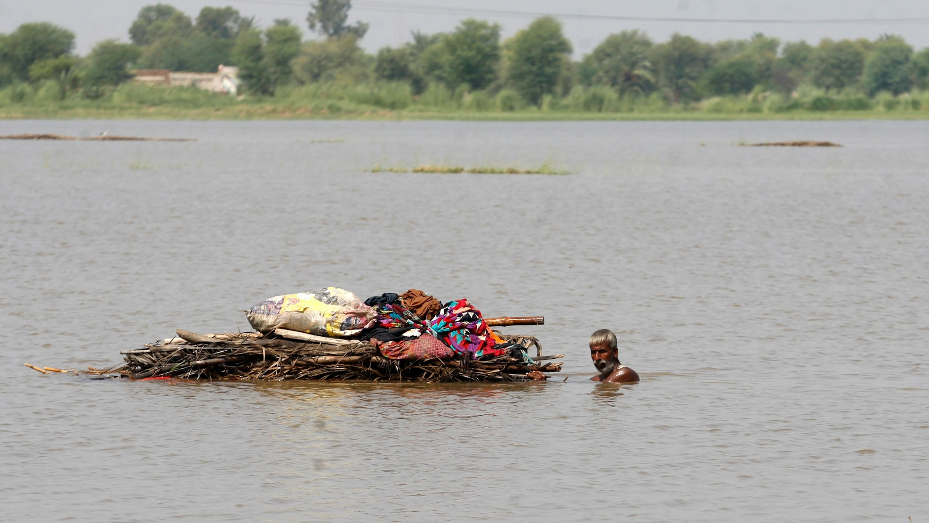Ein Mann in Pakistan transportiert die Habseligkeiten, die er retten konnte auf seinem Floß.