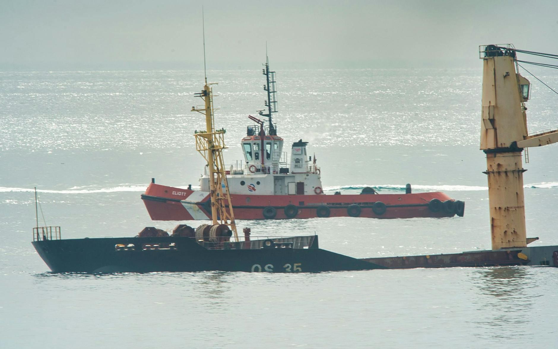 dpatopbilder - Ein Schlepper liegt hinter dem Frachter, der halb gesunken ist.