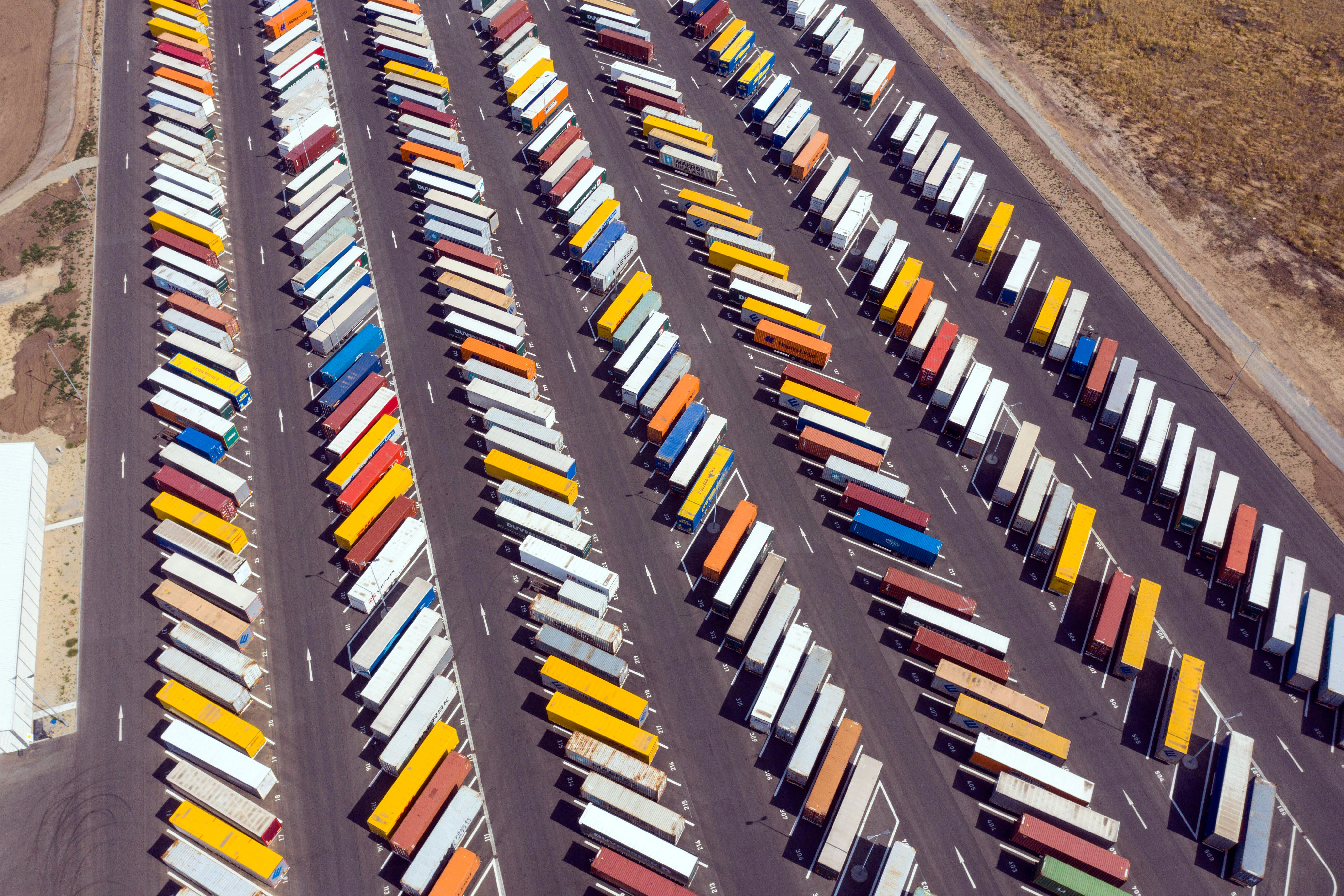Lkw und Container auf einem Parkplatz der Gigafactory in Grünheide.