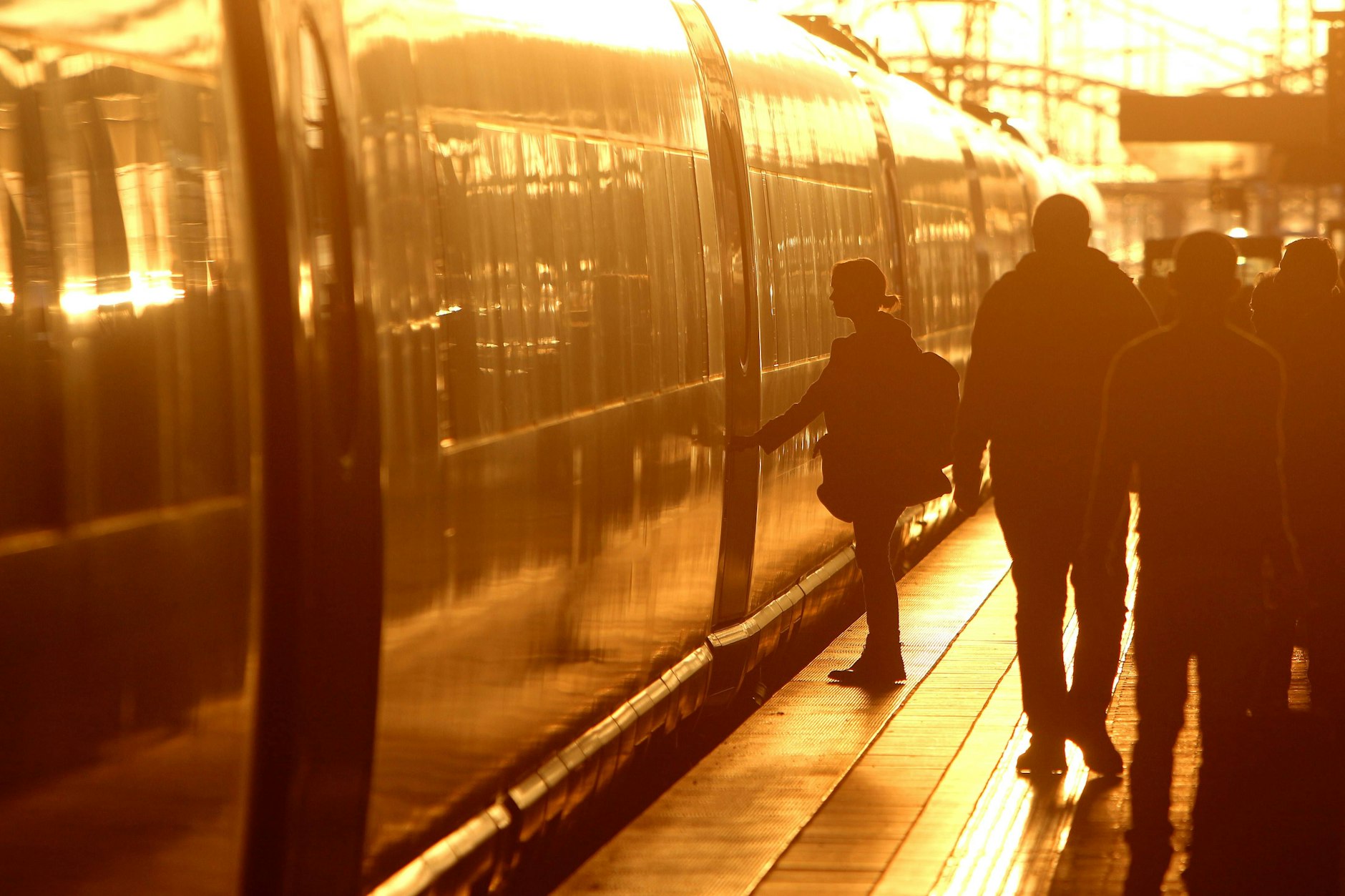 Fahrgäste auf einem Bahnsteig vor einem ICE in der Abendsonne