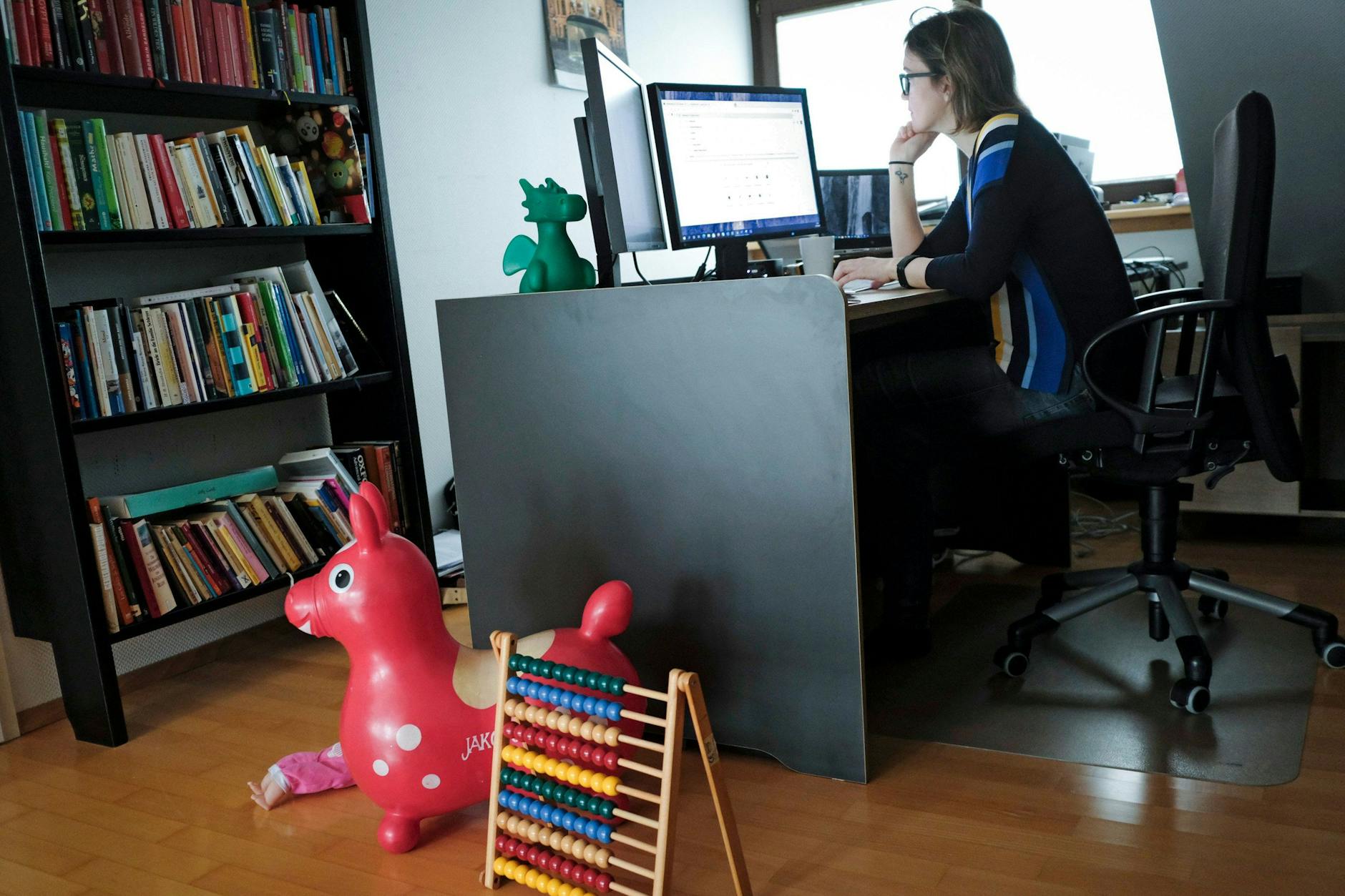 Eine Frau im Home-Office, zu ihren Füßen die Spielzeuge der Kinder.