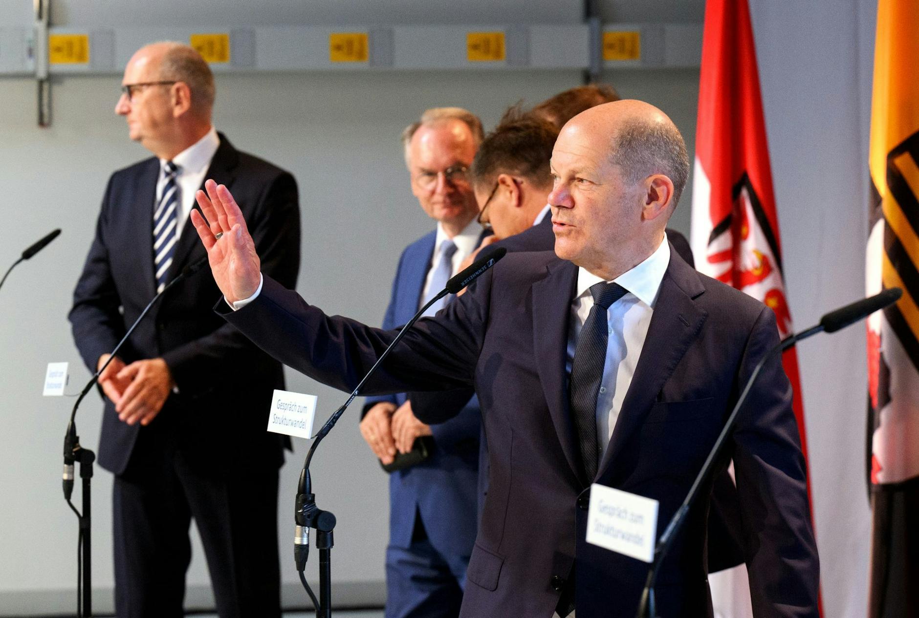 Bundeskanzler Olaf Scholz (SPD, vorne) winkt im Gründerzentrum Dock3 Lausitz zum Ende der Pressekonferenz.