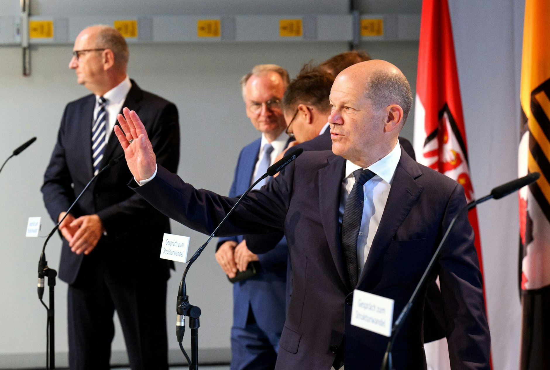 Bundeskanzler Olaf Scholz (SPD, vorne) winkt im Gründerzentrum Dock3 Lausitz zum Ende der Pressekonferenz.  