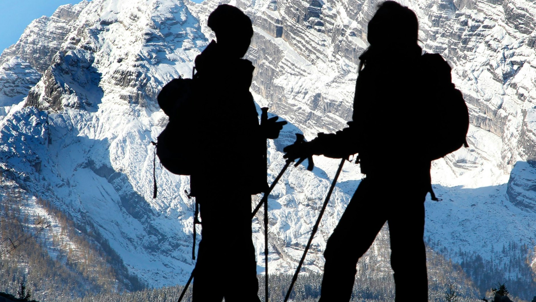 in Mann und eine Frau stehen im Berchtesgadener Land vor der Kulisse der Ostwand des Watzmann. Behörden appellieren, beim Wandern durch das Gebirge die Gefahren richtig einzuschätzen.