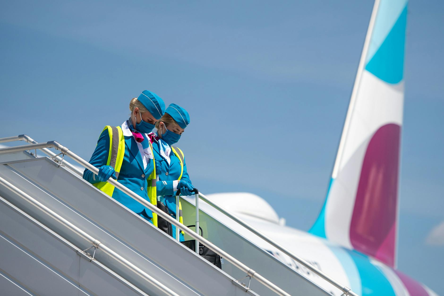  Zwei Flugbegleiterinnen mit Mund-Nasen-Schutz verlassen nach einem Pressetermin ein Flugzeug von Eurowings.