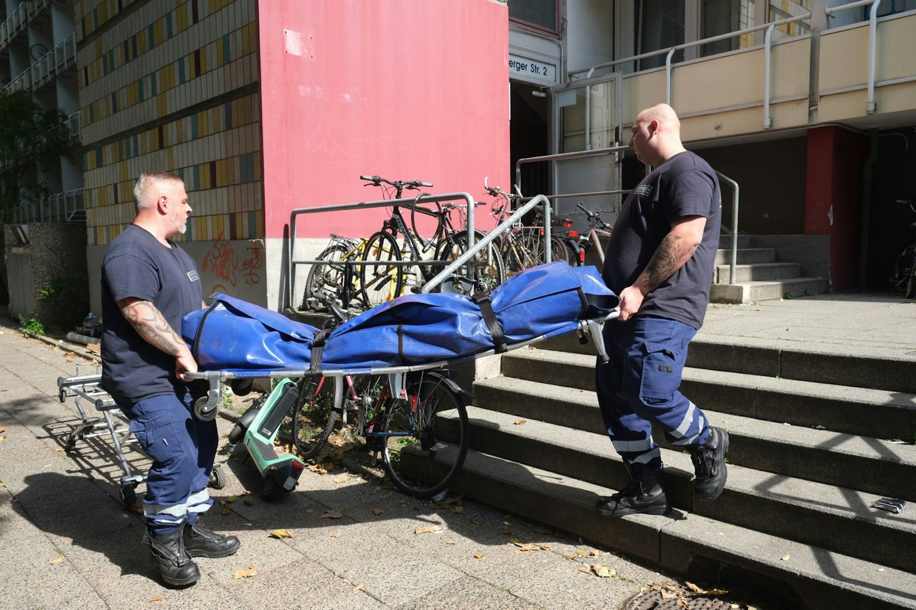 Nach der Tat bringen diese Männer ein tote Person aus dem Gebäude.