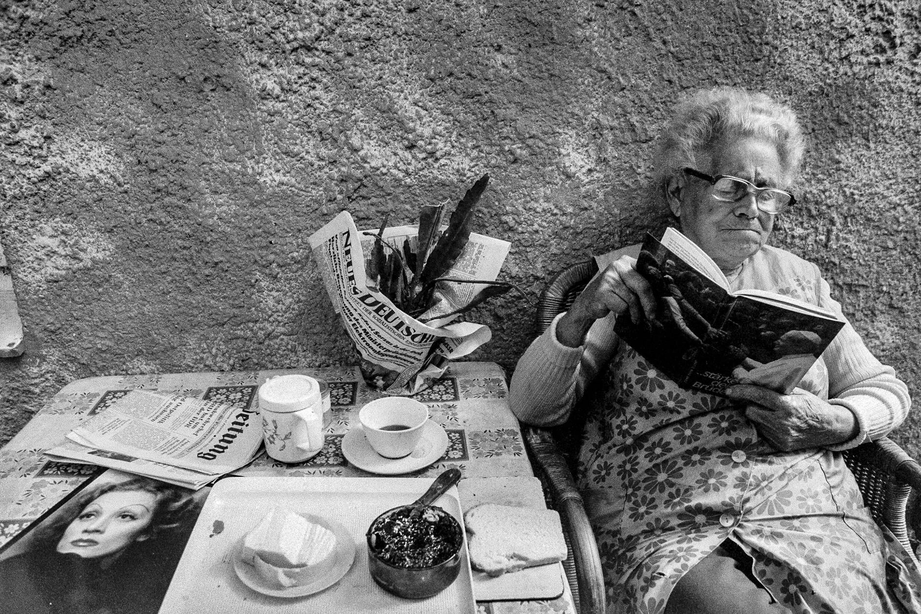 Ein Bild aus der Ausstellung: In einer Kleingartenanlage in Pankow ist eine Rentnerin 1986 in die Lektüre des Buches „... stärke deine Brüder“ von Papst Johannes Paul II. vertieft, das 1982 im katholischen St. Benno Verlag in Leipzig erschienen war.