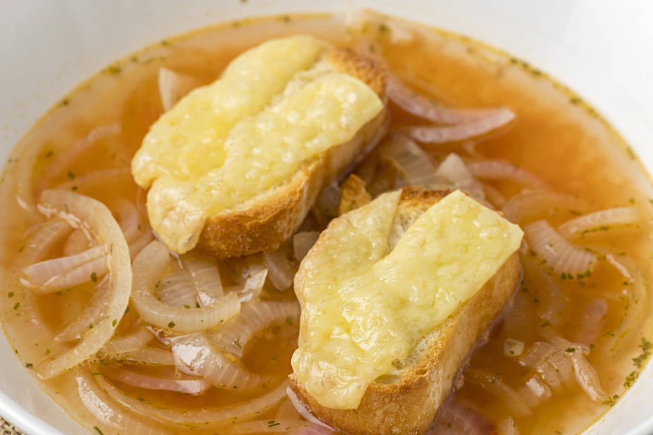 Mit etwas überbackenem Baguette schmeckt die Zwiebelsuppe besonders gut.