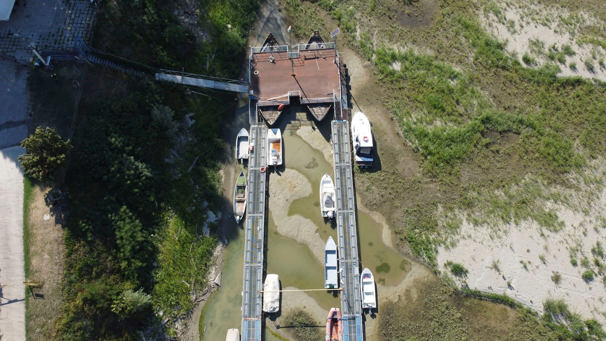 Boote liegen auf dem ausgetrockneten Flussbett an einer Touristenanlegestelle am Fluss Po in Sermide (Italien).  