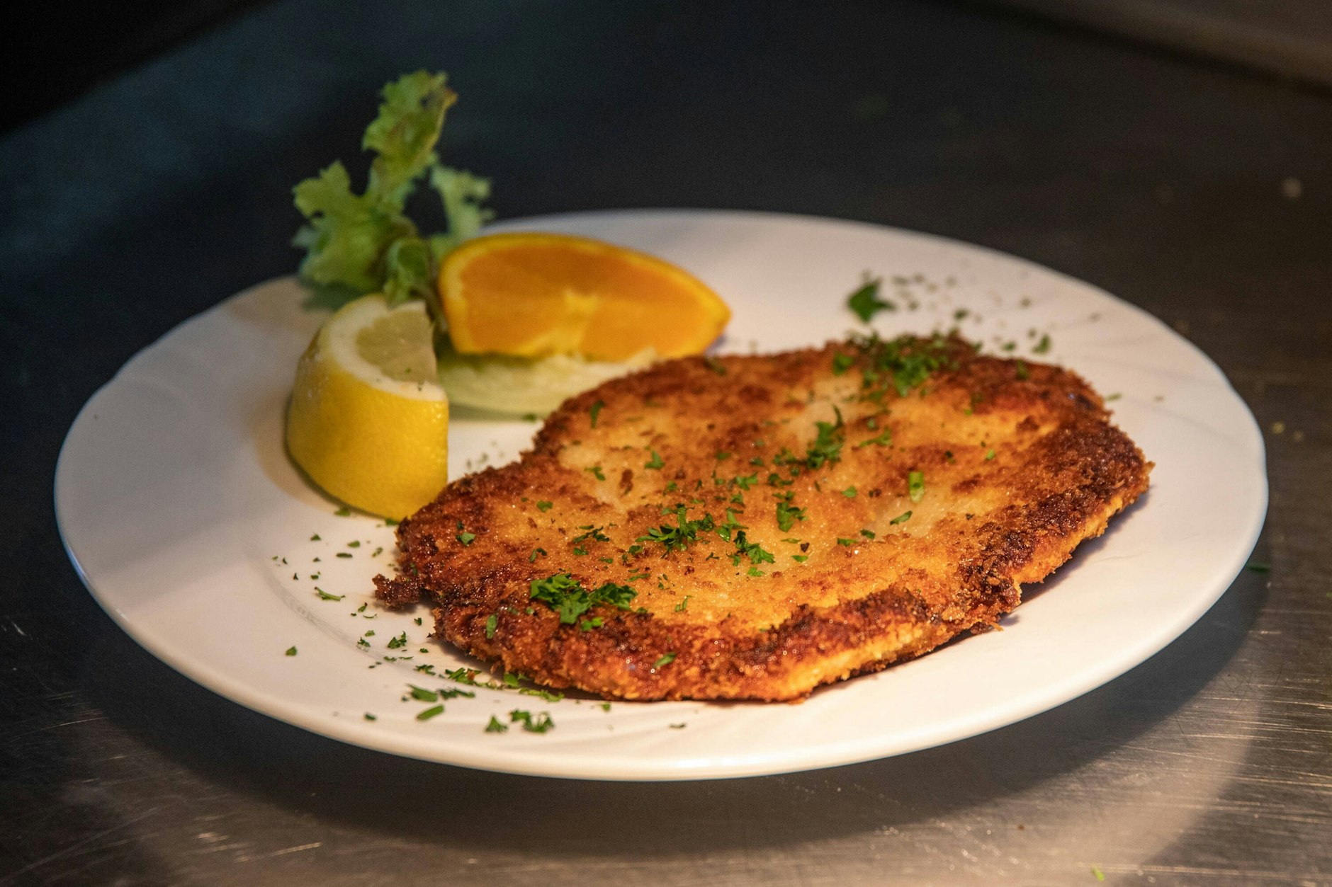 Ein paniertes Schnitzel Wiener Art mit Zitronenscheiben auf einem Teller.
