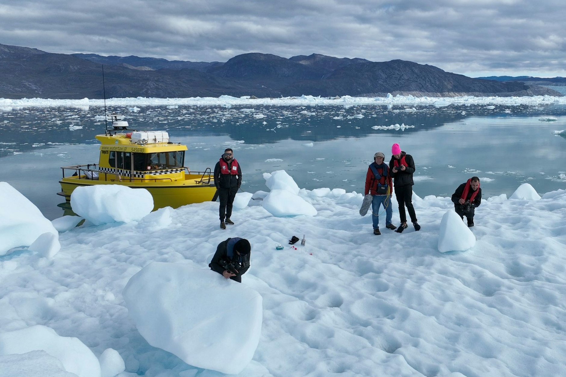 Thilo Mischke mit pinker Mütze und sein Vater mit Mikrofon in der Hand auf einer Eisscholle.