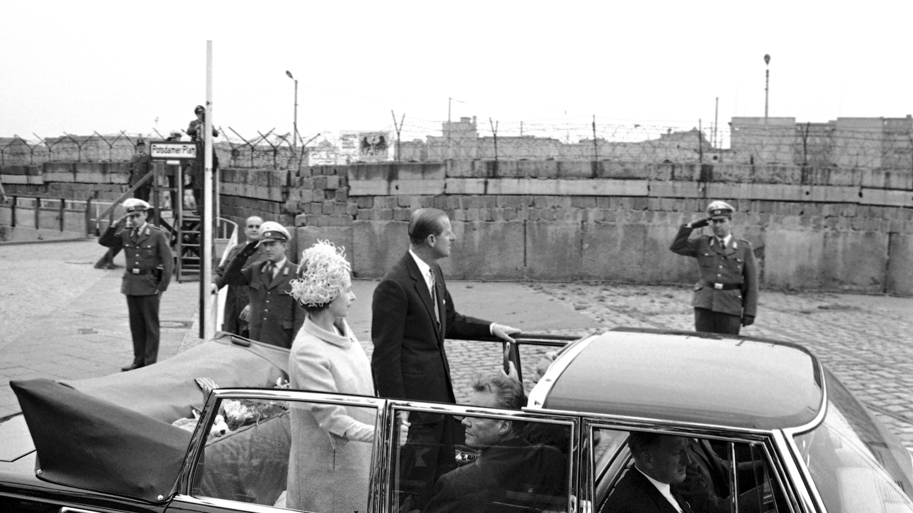 Die britische Königin Elizabeth II. und Prinz Philip fahren während einer Besichtigungstour durch West-Berlin an der Mauer vorbei, die Ost- und Westdeutschland trennt.