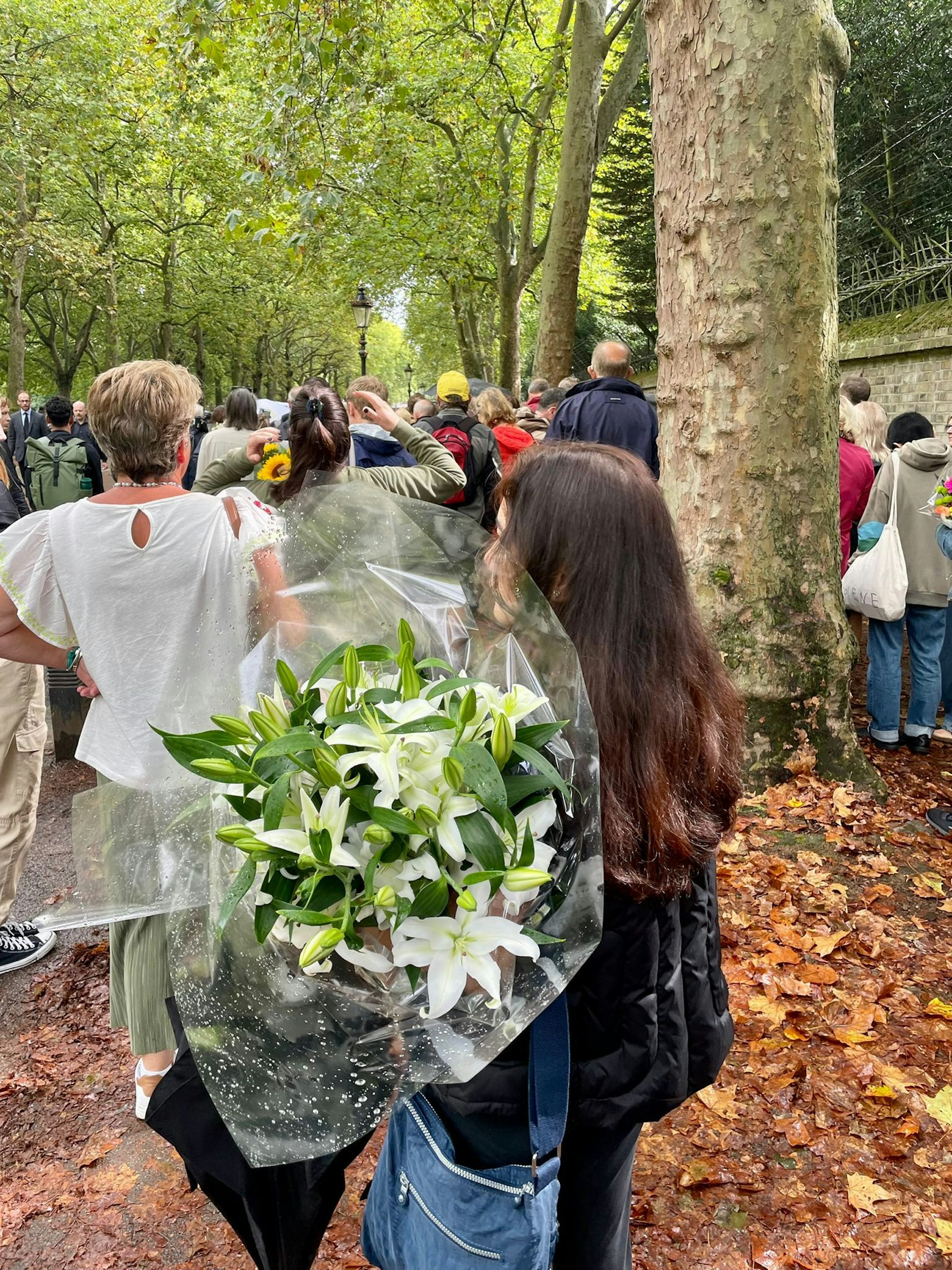 Frau wartet mit Blumenstrauß in der Schlange zum Buckingham-Palast.