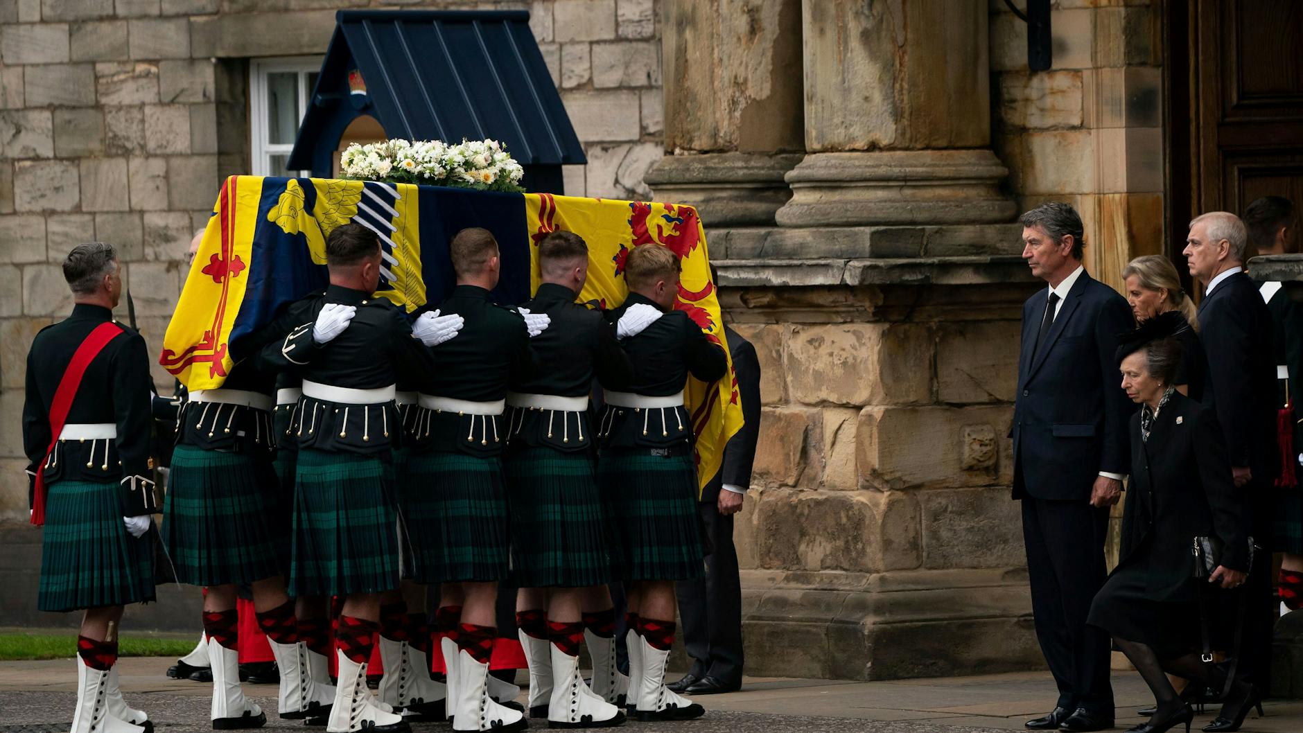 Der Sarg von Queen Elizabeth II. wird in die königliche Residenz Holyroodhouse in Edinburgh getragen. Prinzessin Anne (re.) erweist ihrer verstorbenen Mutter mit einem Knicks die Ehre.