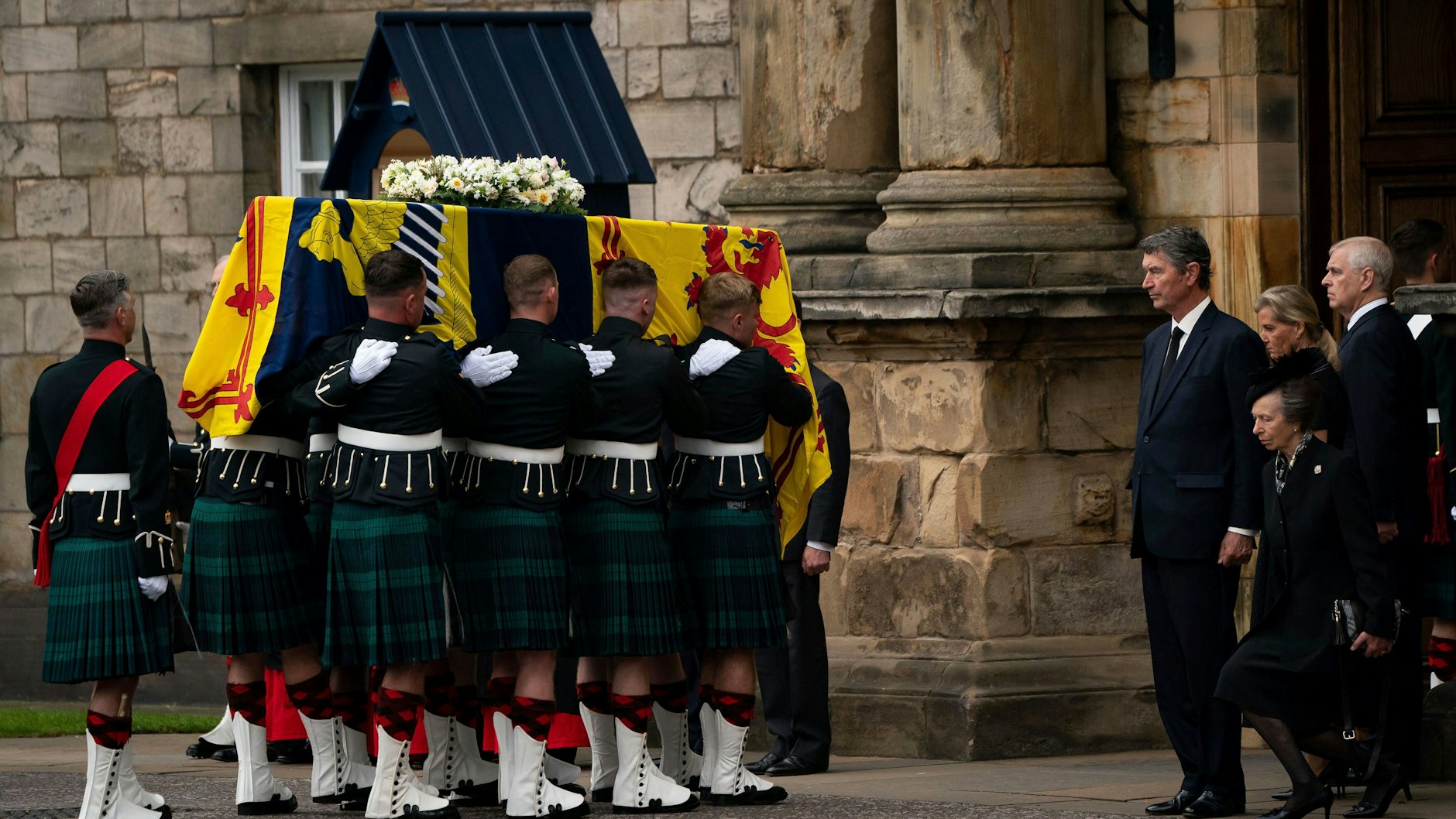 Der Sarg von Queen Elizabeth II. wird in die königliche Residenz Holyroodhouse in Edinburgh getragen. Prinzessin Anne (re.) erweist ihrer verstorbenen Mutter mit einem Knicks die Ehre.