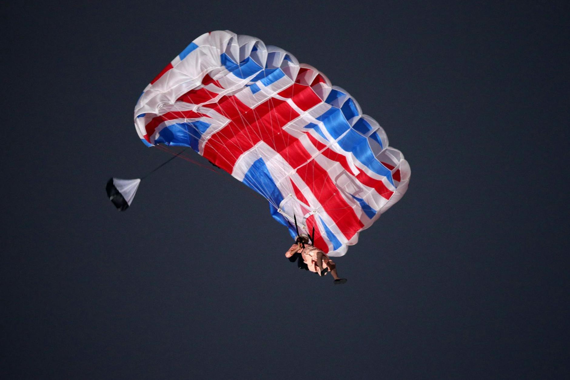 Ein Schauspieler, verkleidet als britische Königin Elizabeth II., schwebt bei der Eröffnungsfeier der Olympischen Spiele in London mit einem Fallschirm ein.