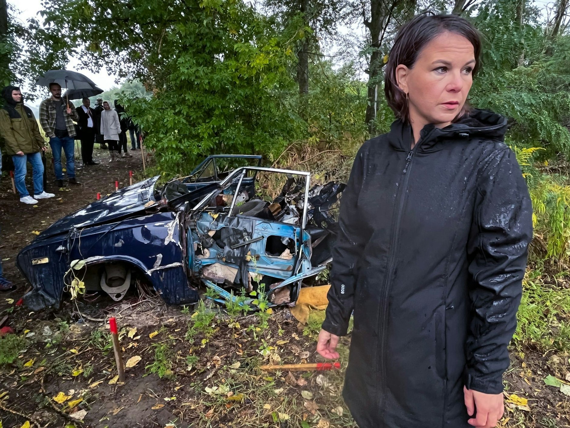 Außenministerin Annalena Baerbock besichtigt ein von Deutschland gefördertes Minenräumprojekt in der Nähe von Kiew. Das Auto im Hintergrund ist durch eine Mine zerstört worden.