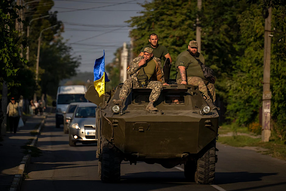 Soldaten der ukrainischen Armee sitzen auf einem gepanzerten Militärfahrzeug.  