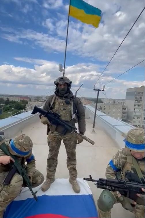 Ukrainische Soldaten haben auf dem Dach eines Hauses in Kupjansk ihre Flagge gehisst und sich auf die russische Fahne gestellt.