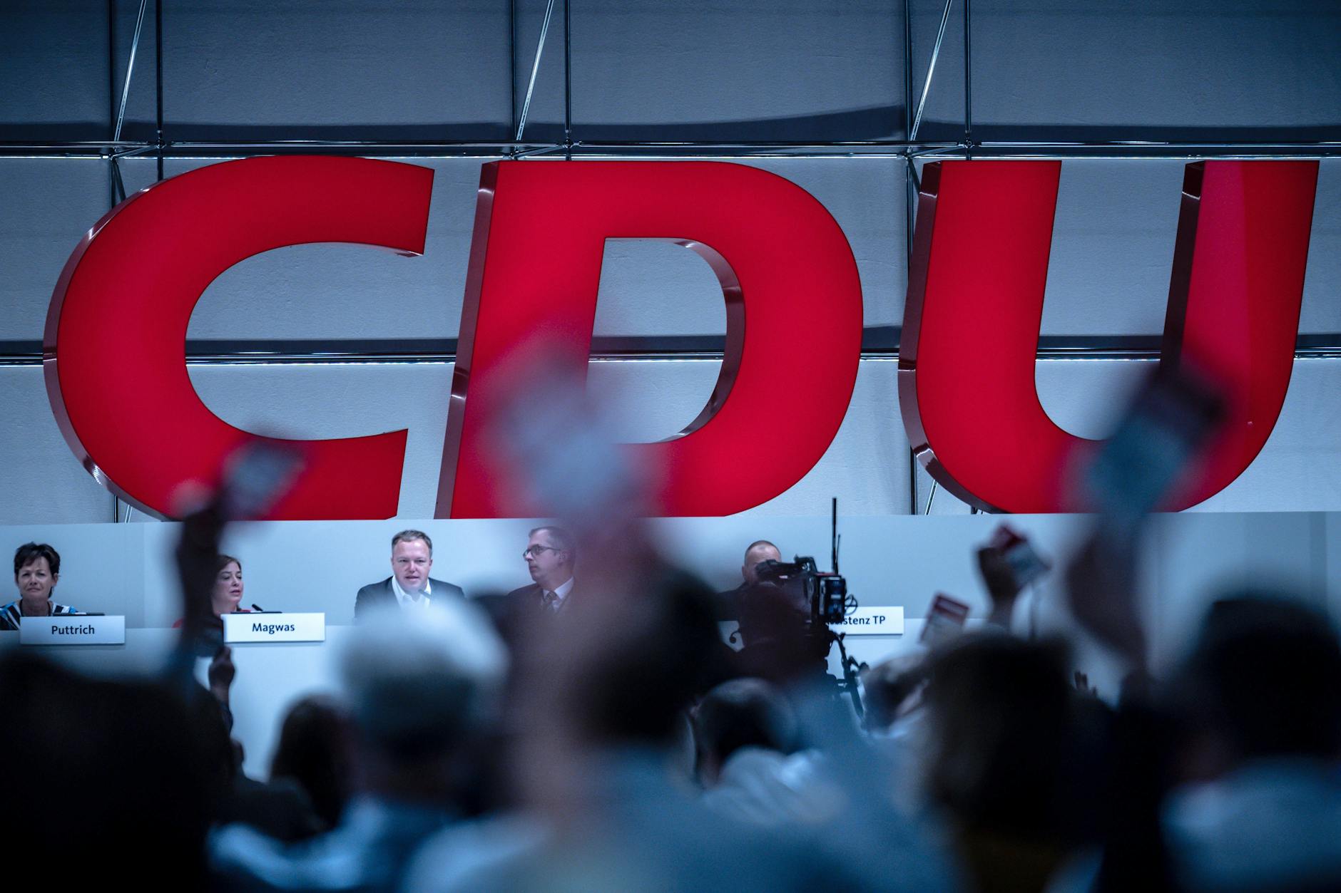 Delegierte halten beim Bundesparteitag der CDU ihre Stimmkarten hoch.