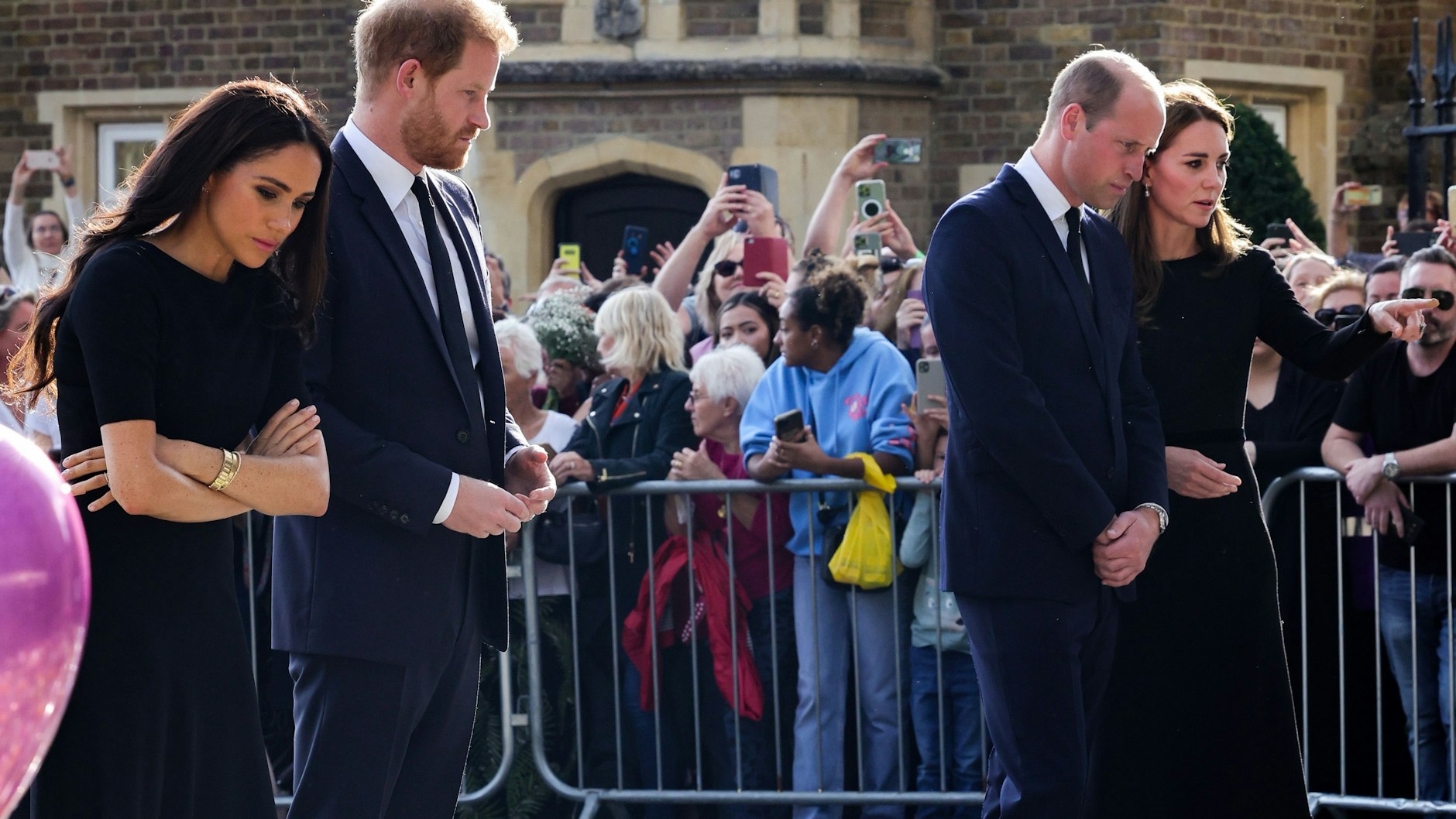 Meghan und Prinz Harry, Herzogenpaar von Sussex, und der britische Thronfolger William, Prinz von Wales, und seine Frau Kate, Prinzessin von Wales, betrachten die Blumen und letzte Grüße, die Trauernde auf Schloss Windsor nach dem Tod der Königin niedergelegt haben.