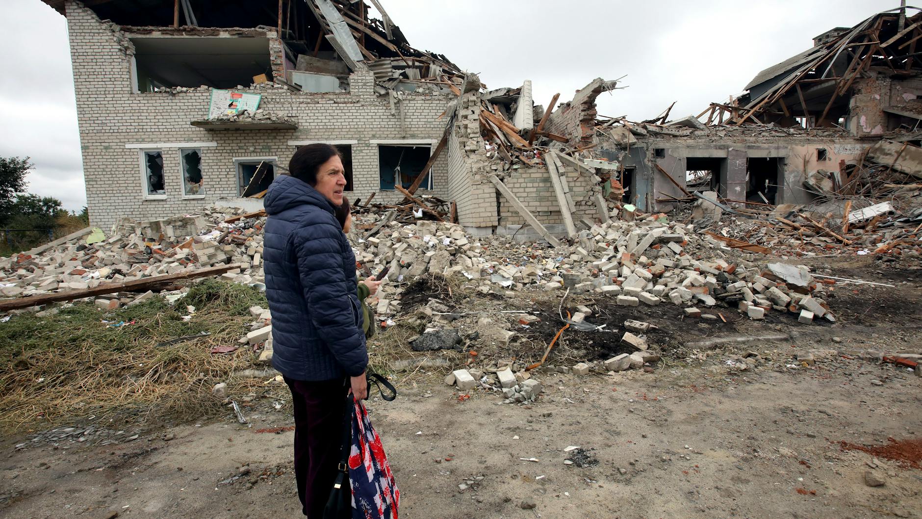Menschen stehen im ukranischen Ort Werbiwka vor einem Lyzeum, das durch Beschuss von russischen Truppen zerstört wurde. 