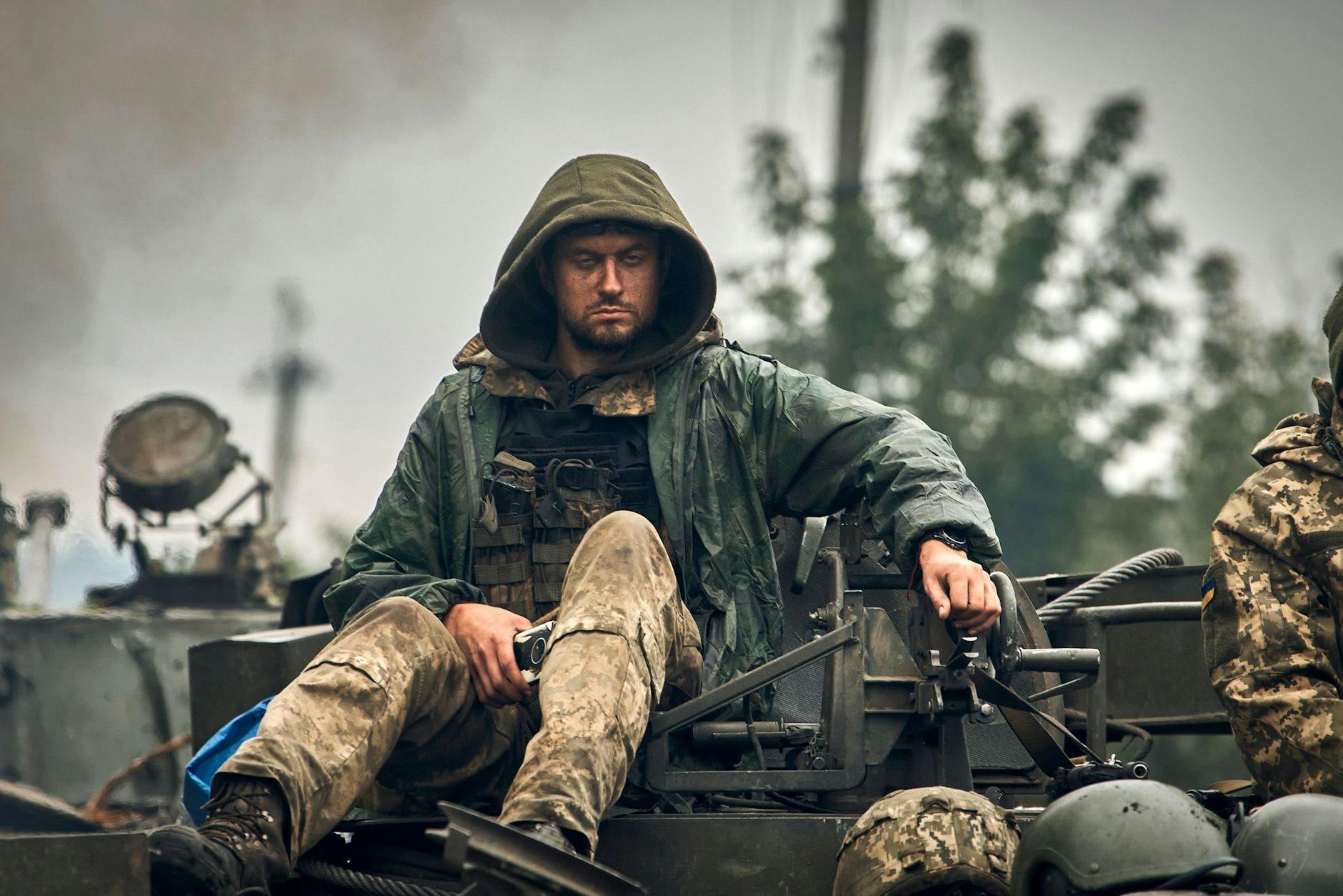 Erschöpft und schmutzig sitzt ein ukrainischer Soldat auf einem Militärfahrzeug. Seine Führung wünscht sich von Deutschland Kampfpanzer.
