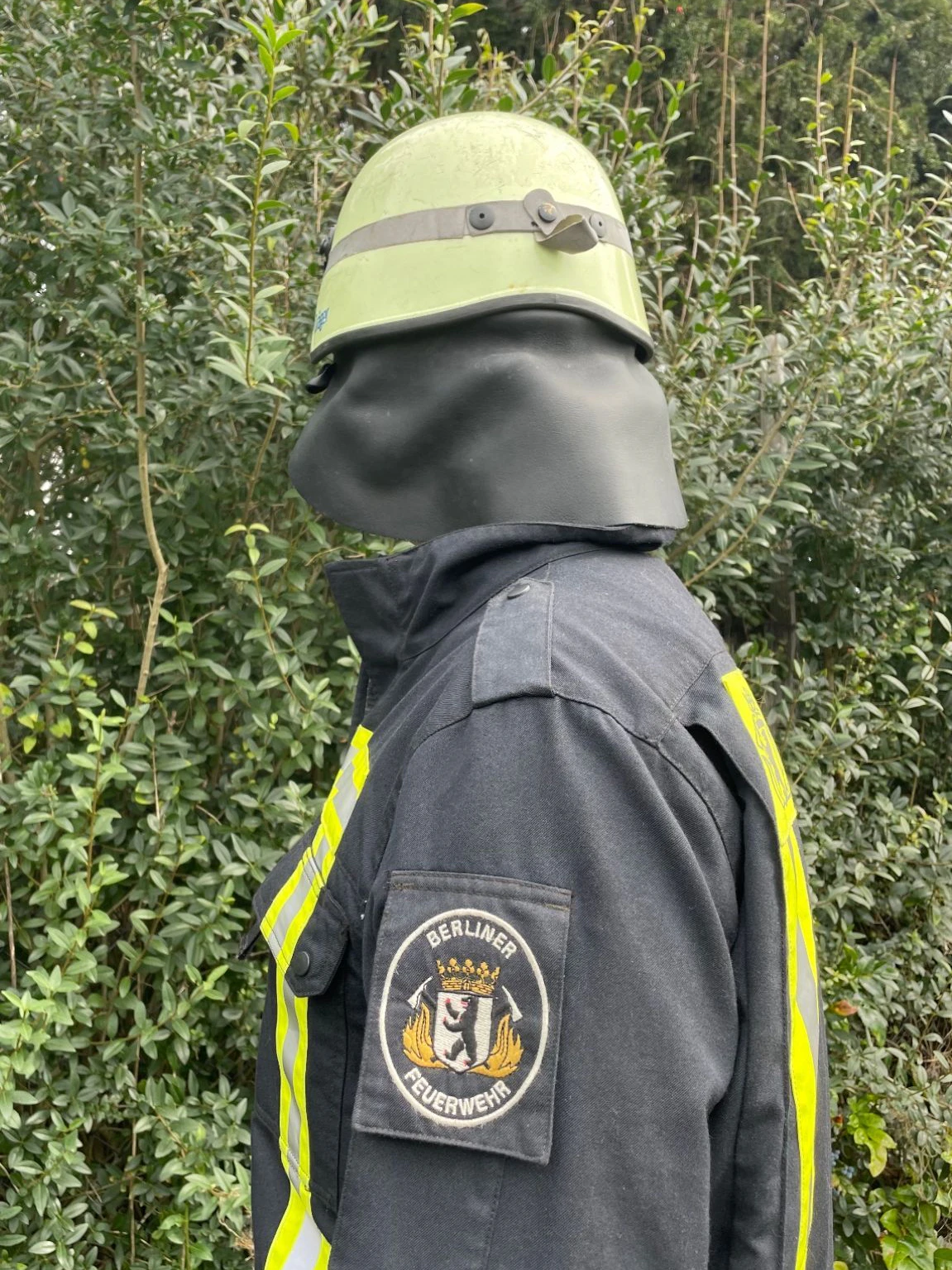 Der Retter der Berliner Feuerwehr in Einsatzkleidung mit Abzeichen und Helm.