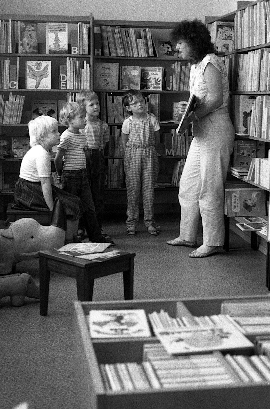 Bibliothekarin zeigt einer Gruppe Vorschulkindern ein Buch.