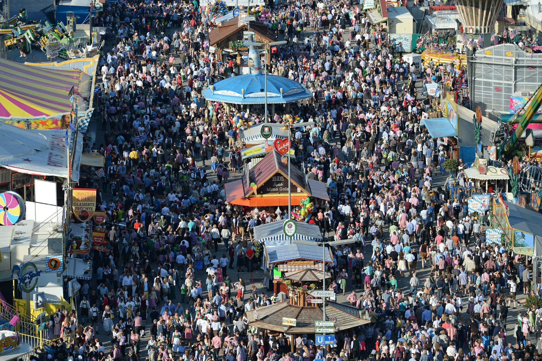 Zahlreiche Menschen gehen bei Sonnenschein über das Oktoberfest-Gelände.
