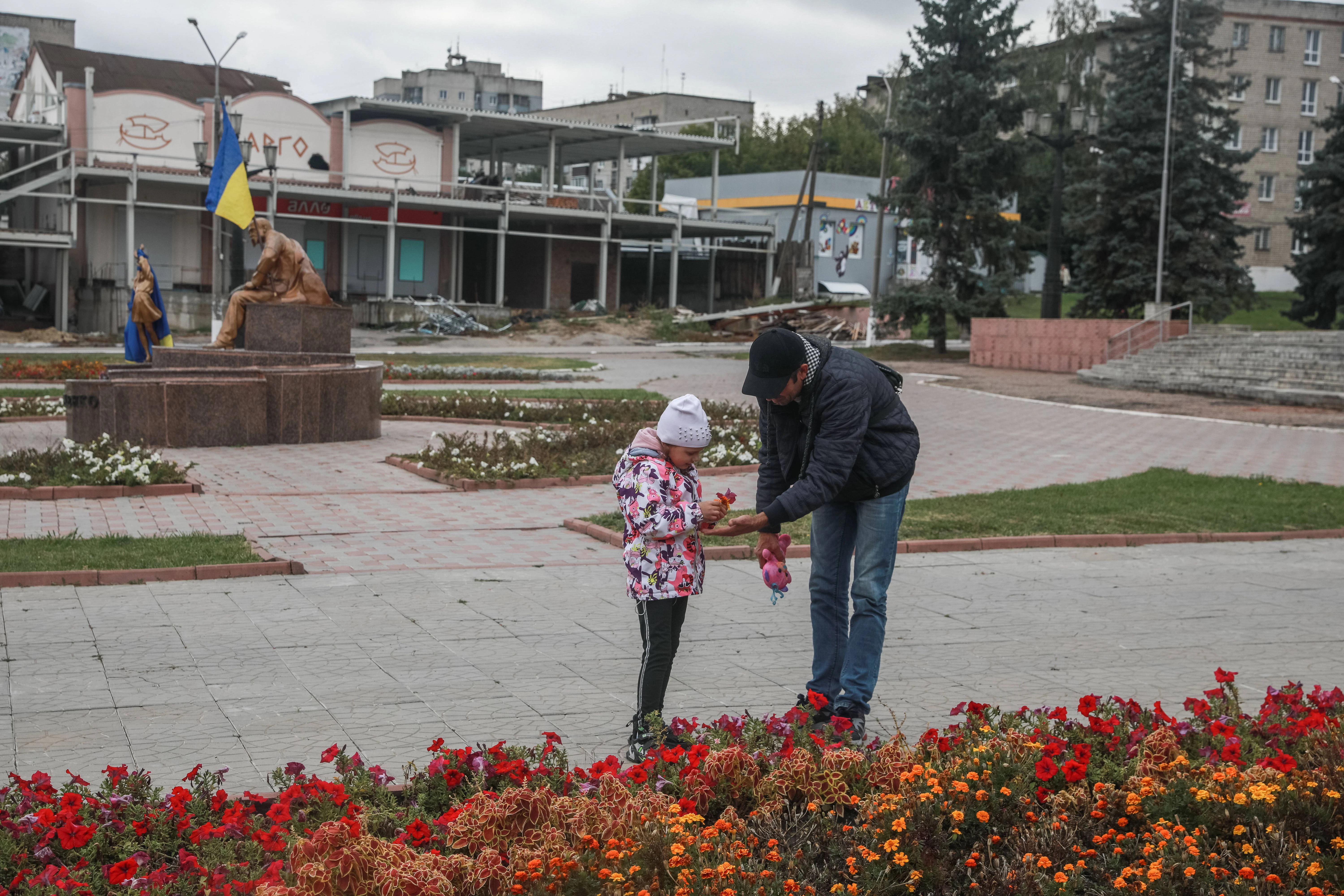 In der von den russischen Soldaten befreiten Stadt Balakliya, Region Charkiw. Vater und Tocher sammeln Blumen.